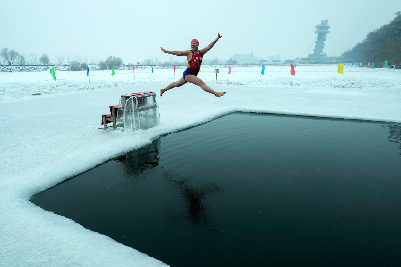 Yu Xiaofeng leaps as she jumps into a pool carved from ice on the frozen Songhua river in Harbin in northeastern China's Heilongjiang province, Tuesday, Jan. 7, 2025. (AP Photo/Andy Wong)