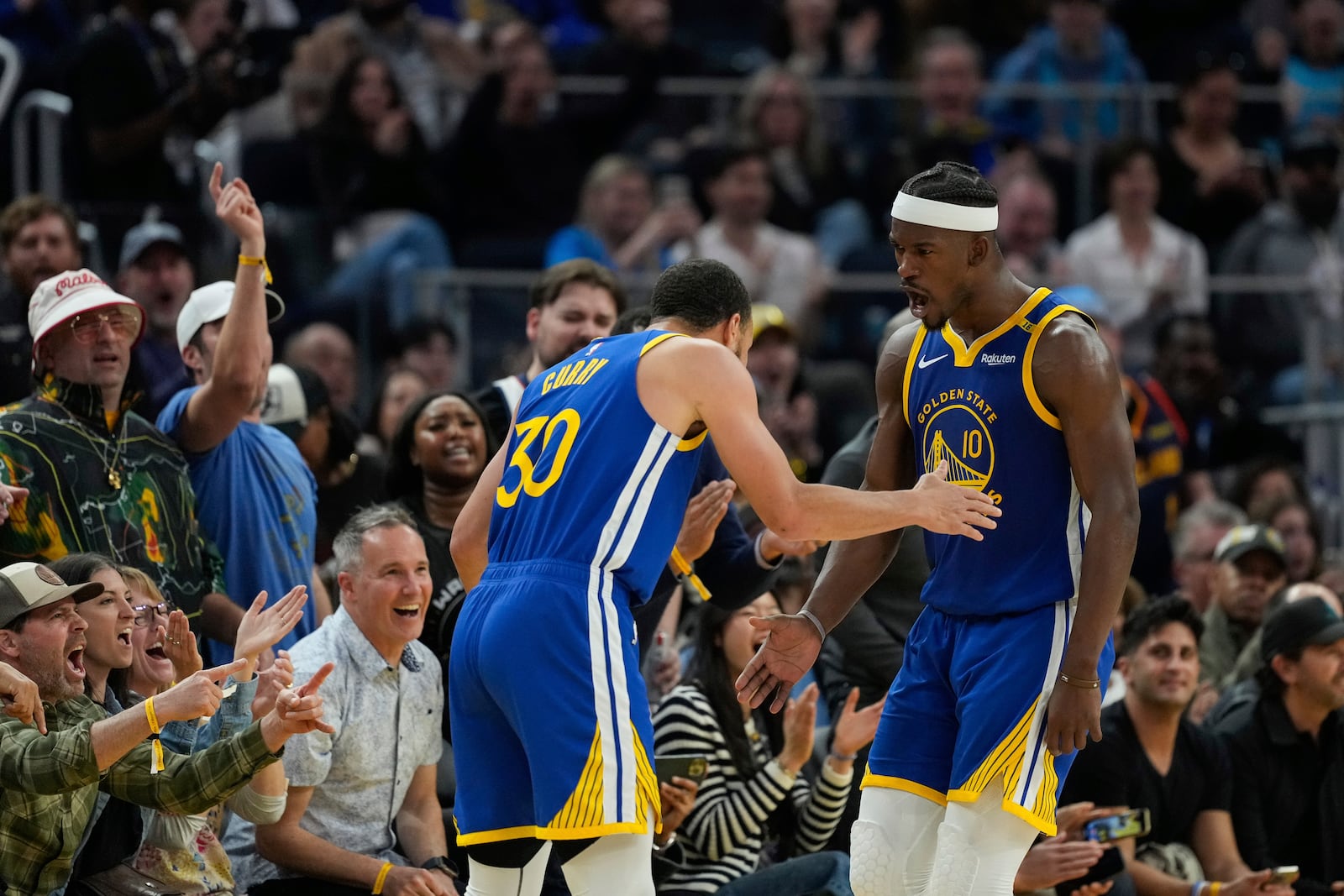 Golden State Warriors forward Jimmy Butler III, right, celebrates with guard Stephen Curry (30) after scoring during the first half of an NBA basketball game against the Dallas Mavericks, Sunday, Feb. 23, 2025, in San Francisco. (AP Photo/Godofredo A. Vásquez)