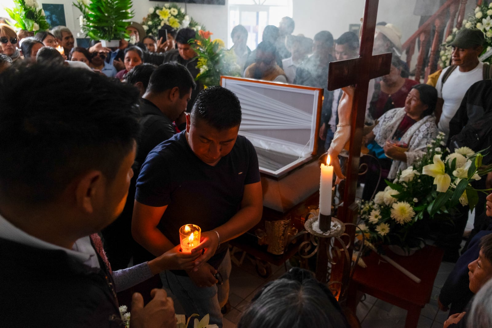 A man lights a candle next to the coffin of slain Catholic priest and activist Marcelo Pérez at the Pérez family's house, in San Andrés Larráinzar, Chiapas state, Mexico, Monday, Oct. 21, 2024. (AP Photo/Isabel Mateos)