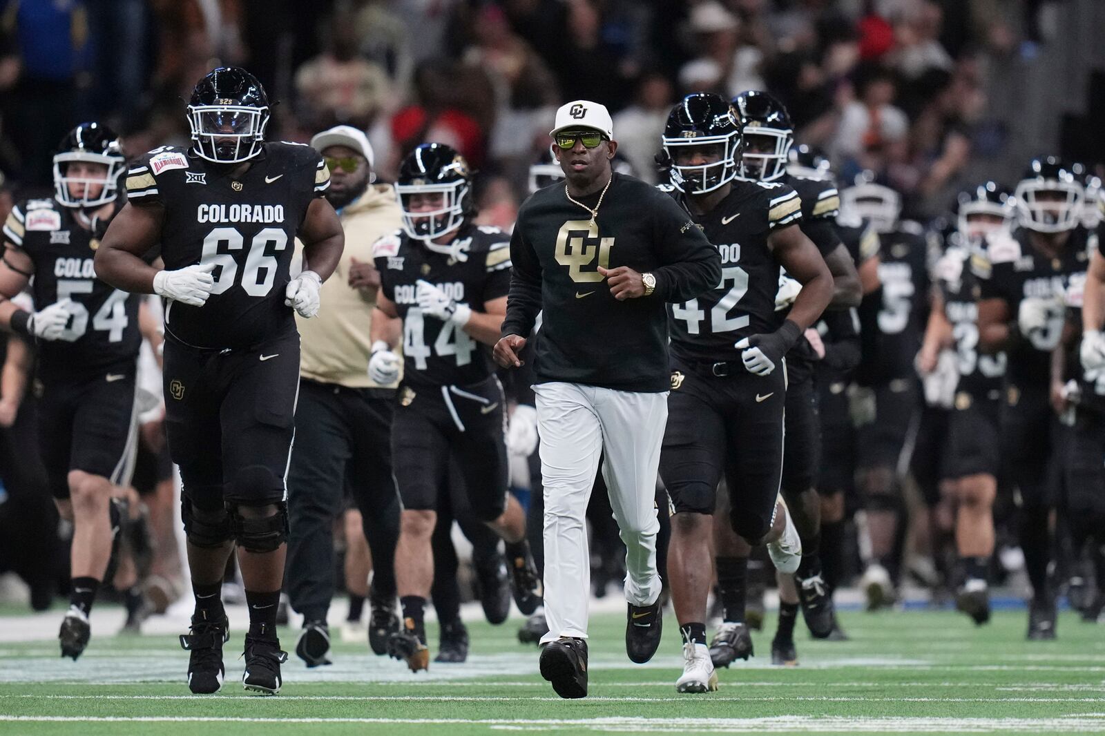 Colorado head coach Deion Sanders, center, takes the field with his team before the Alamo Bowl NCAA college football game against BYU, Saturday, Dec. 28, 2024, in San Antonio. (AP Photo/Eric Gay)