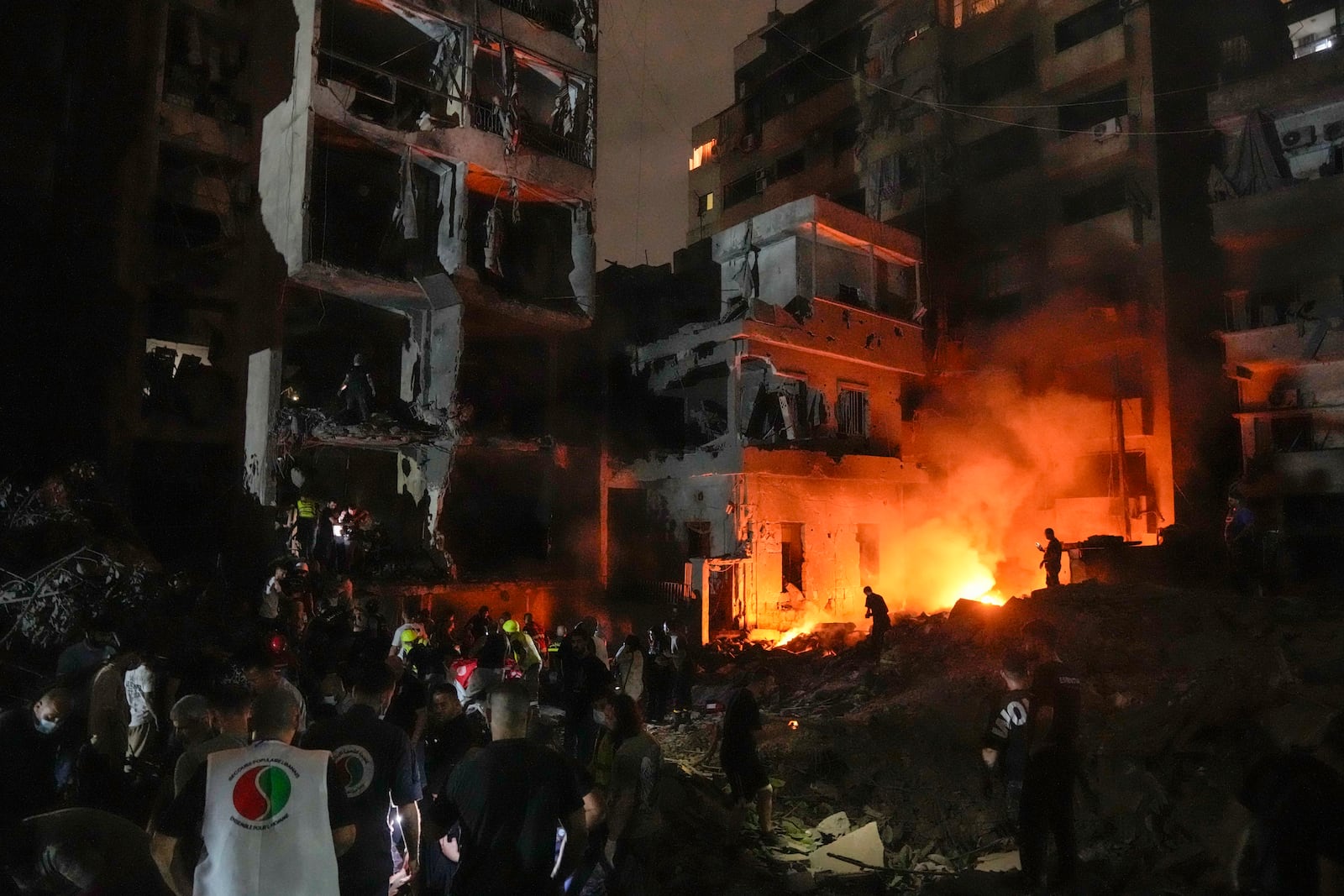 People gather in front of destroyed buildings hit by an Israeli airstrike in central Beirut, Lebanon, Thursday, Oct. 10, 2024. (AP Photo/Bilal Hussein)