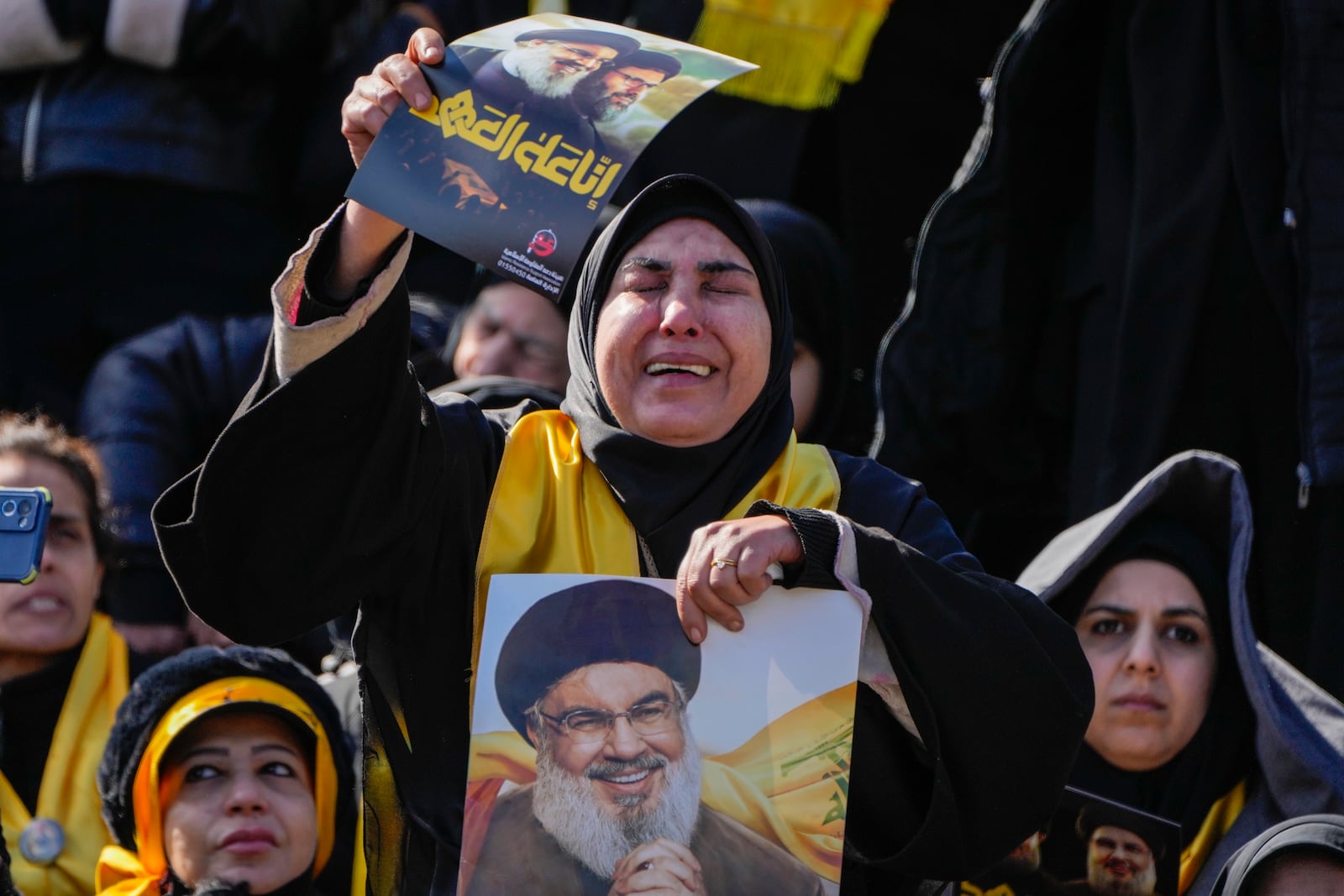 Mourners react as a trailer carrying the coffins containing the bodies of Hezbollah's former leader Hassan Nasrallah and his cousin and successor Hashem Safieddine drives through the crowd at the beginning of a funeral procession in the Sports City Stadium in Beirut, Lebanon, Sunday, Feb. 23, 2025. (AP Photo/Hussein Malla)