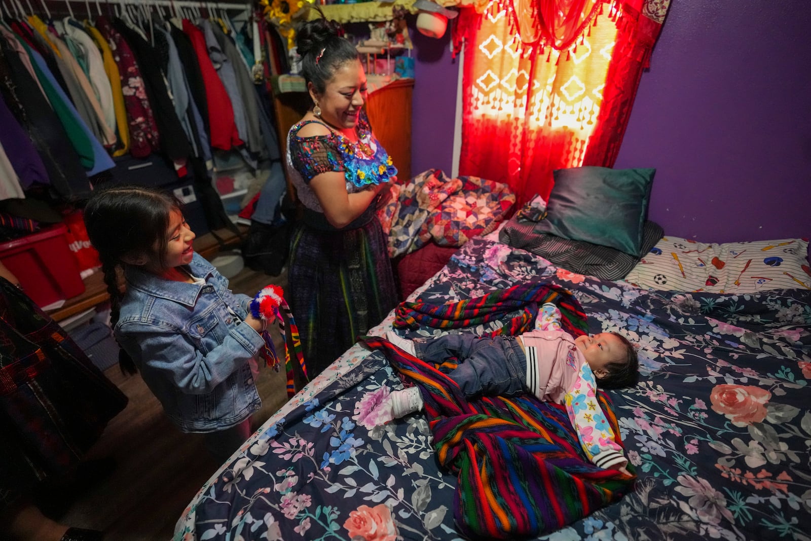 Arely Lopez, her baby Alejandra and older daughter Carol change back into casual clothes at Arely's brother-in-law's home in Worthington, Minnesota, Sunday, Jan. 12, 2025, as they get ready for an hours-long drive home after attending the celebration of the feast day of Guatemala's Black Christ of Esquipulas. (AP Photo/Abbie Parr)