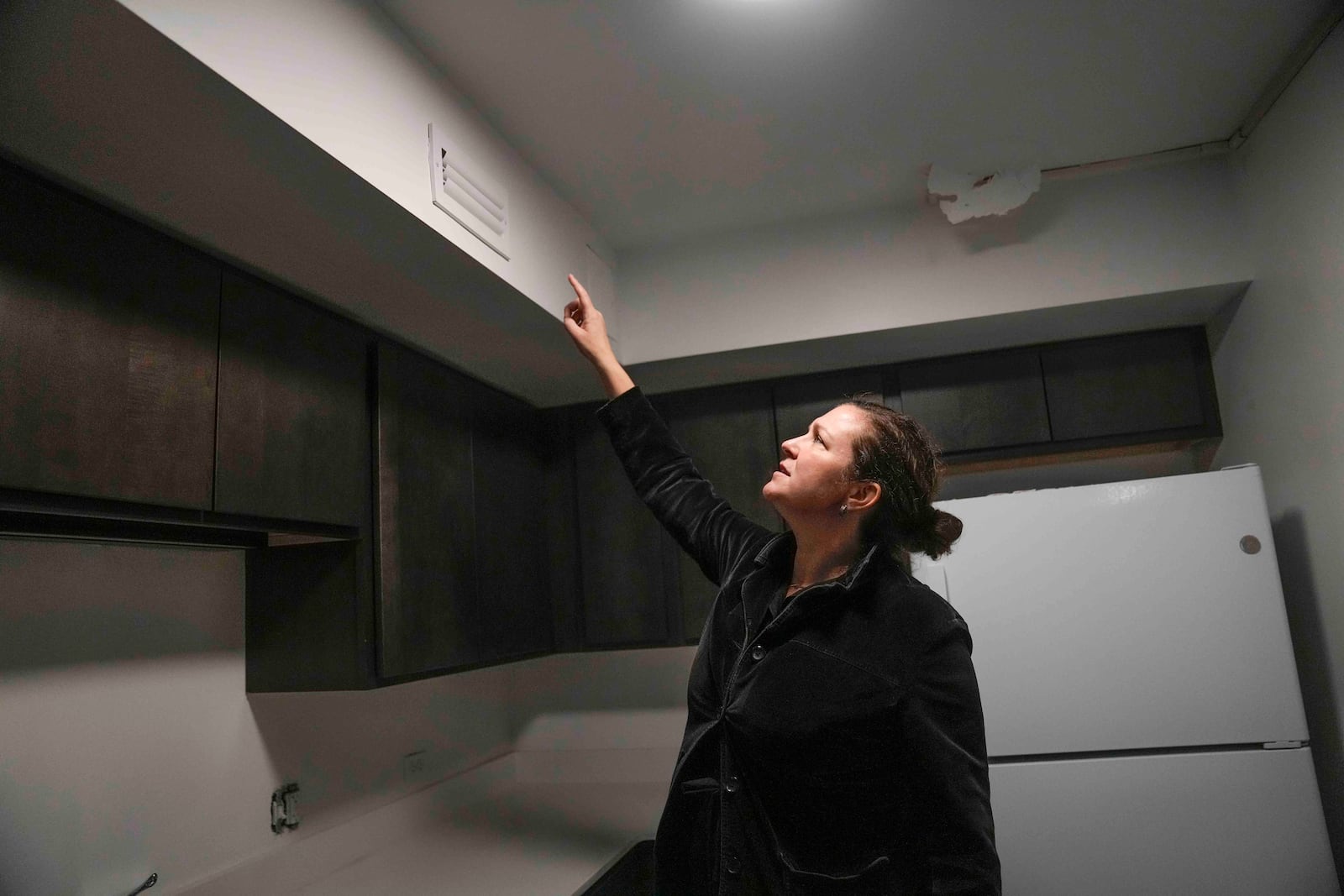 Molly Ekerdt, vice president of the Preservation of Affordable Housing Chicago office points at a vent that will provide fresh air through a duct system in a recently renovated unit in the Island Terrance Apartments, Monday, Nov. 18, 2024, in Chicago. (AP Photo/Erin Hooley)