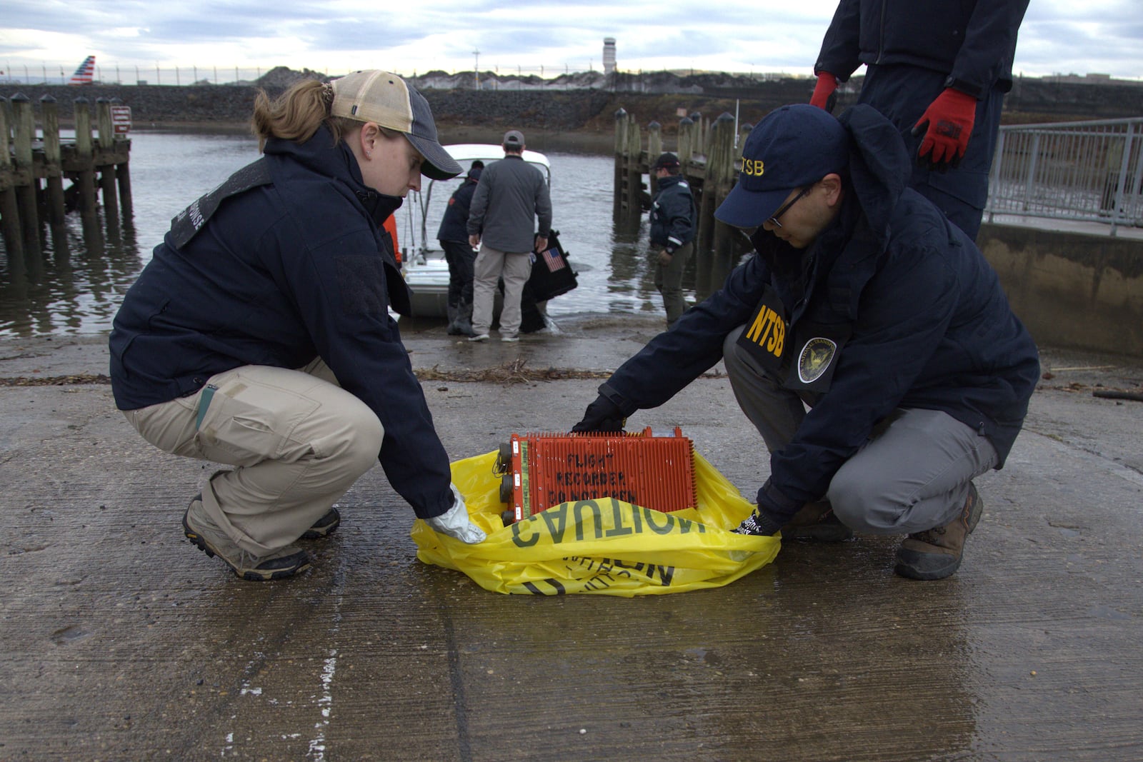 In this undated image provided by the National Transportation Safety Board, NTSB investigators examine a flight data recorder recovered from the wreckage of a mid-air collision between an Army Black Hawk helicopter and an American Airlines jet Wednesday night, Jan. 29, 2025, near Ronald Reagan Washington National Airport in Arlington, Va. (NTSB via AP)