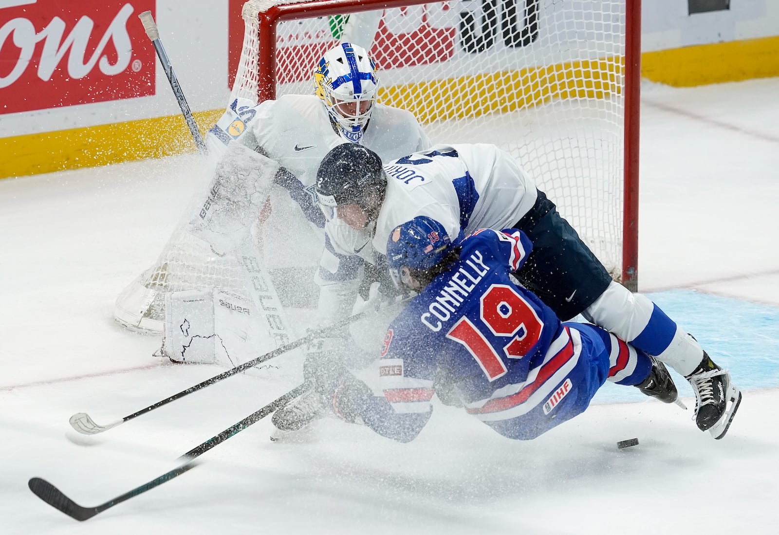 Finland defenseman Mitja Jokinen (2) takes down United States forward Trevor Connelly (19) in front of Finland goaltender Petteri Rimpinen, top, during first-period IIHF World Junior Hockey Championship gold medal game action in Ottawa, Ontario, Sunday, Jan. 5, 2025. (Adrian Wyld/The Canadian Press via AP)