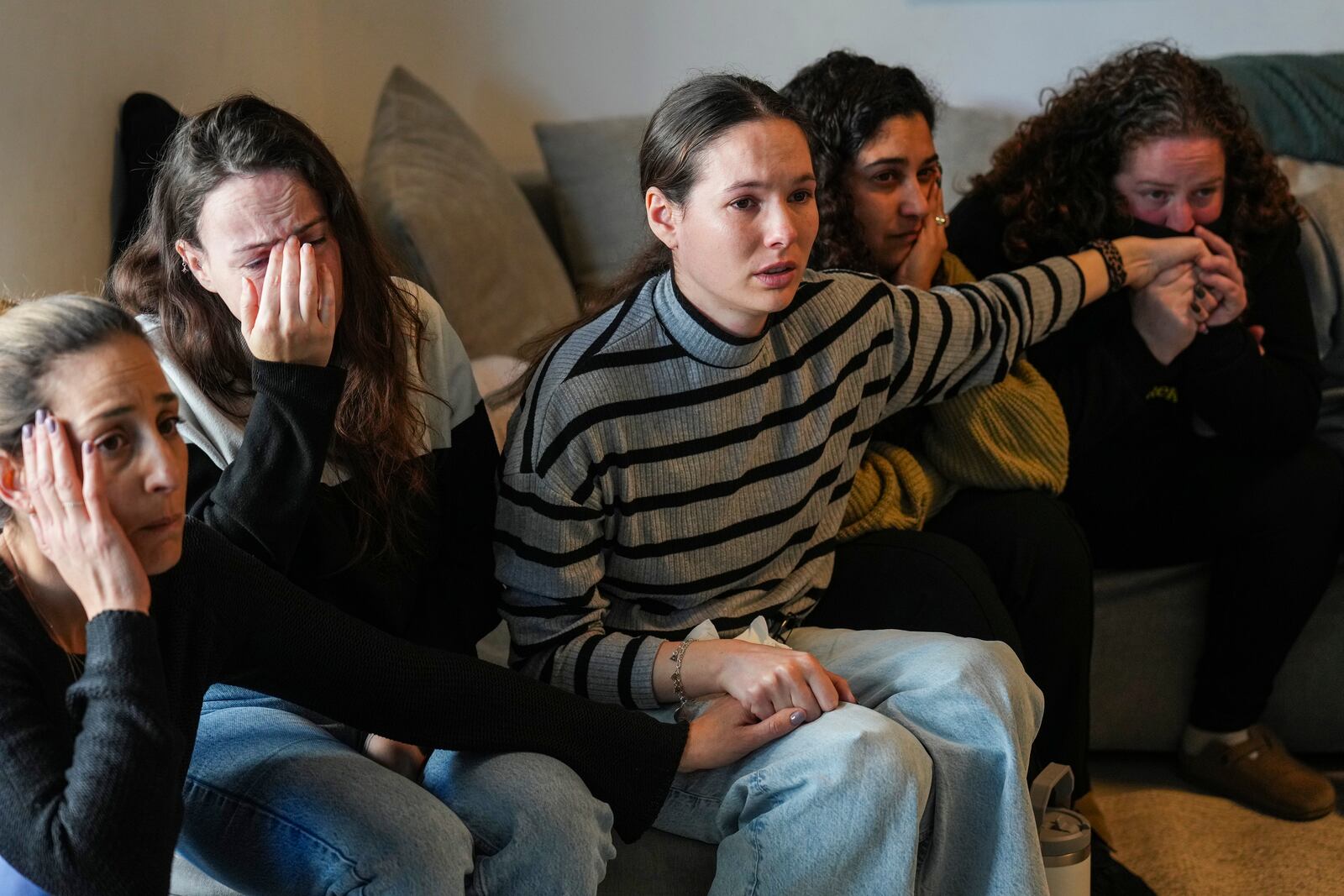 Freed hostage Shani Goren, right, and friends of Israeli hostage Arbel Yehoud react as they watch the broadcast of her being released from Hamas captivity, in Carmei Gat, southern Israel, Thursday, Jan. 30, 2025, as part of the Israel-Hamas ceasefire deal. (AP Photo/Ariel Schalit)