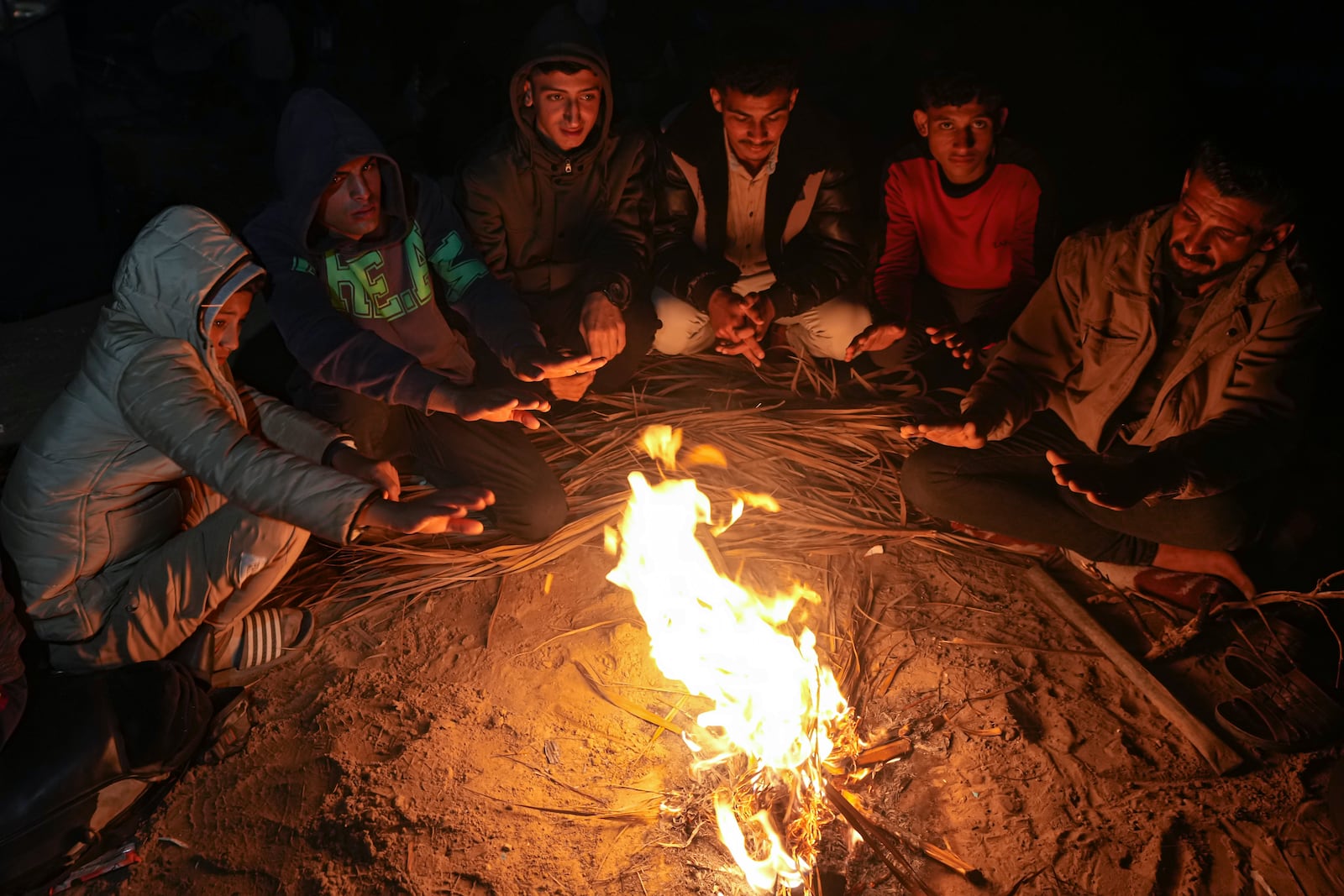 Displaced Palestinians warm themselves by a fire near a roadblock, as they wait to return to their homes in the northern part of the Gaza Strip, Sunday, Jan. 26, 2025, days after the ceasefire deal between Israel and Hamas came into effect. (AP Photo/Abdel Kareem Hana)