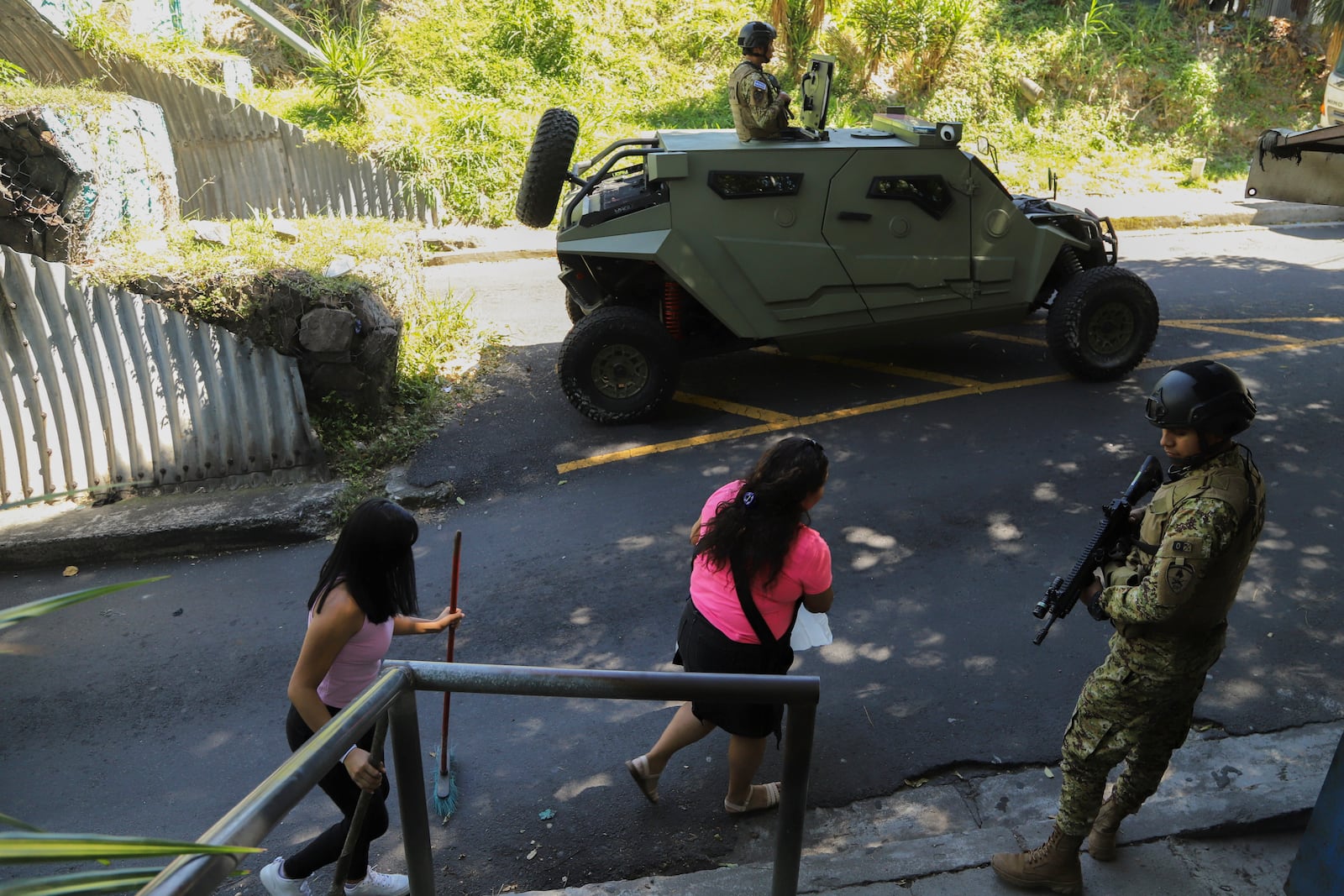 Residents in the 10 de Octubre neighborhood pass by Salvadoran soldiers during a government deployment of soldiers and police to crack down on gangs in San Marcos, El Salvador, Monday, Oct. 28, 2024. (AP Photo/Salvador Melendez)