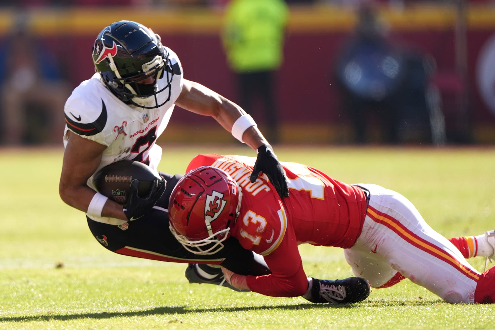 Houston Texans wide receiver Robert Woods (2) is tackled by Kansas City Chiefs cornerback Nazeeh Johnson (13) during the first half of an NFL football game Saturday, Dec. 21, 2024, in Kansas City, Mo. (AP Photo/Charlie Riedel)