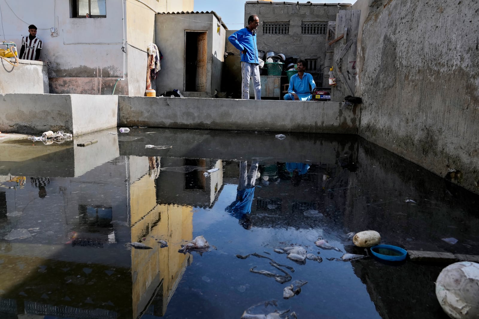 Former local councillor Qadir Baksh, center, talks with his brother Amanullah who starts a generator to drain water from their neighborhood of Gwadar, Pakistan, Tuesday, Jan. 14, 2025. (AP Photo/Anjum Naveed)