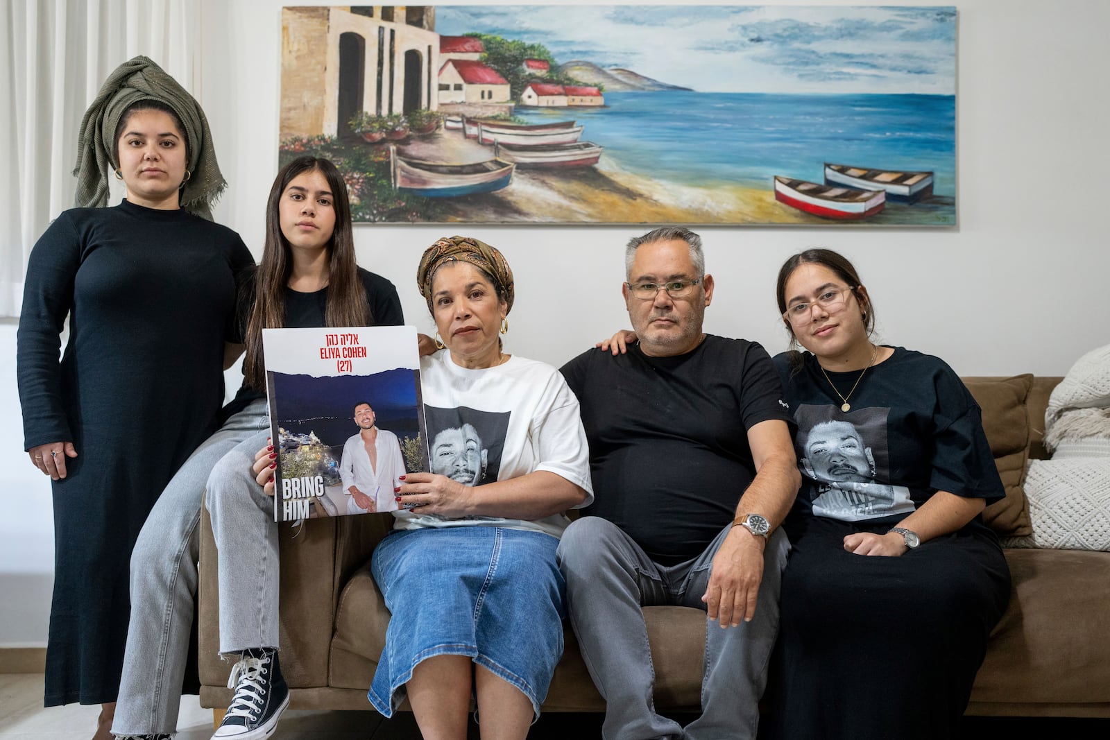 FILE - Sigi and Momi Cohen, flanked on the couch by their children Yuval, Michal, and Tamar, hold up a portrait of their 27-year-old son, Eliya Cohen, in the family house in the village of Tzur Hadassah, Israel, Oct. 30, 2023. Cohen, an Israeli citizen, was abducted by Hamas militants from the "Nova" Music Festival near Kibbutz Re'im, Hamas fighters during the group's attack on Oct. 7 that resulted in the killing of over 1,400 people and the abduction of over 220. (AP Photo/Ohad Zwigenberg, File)