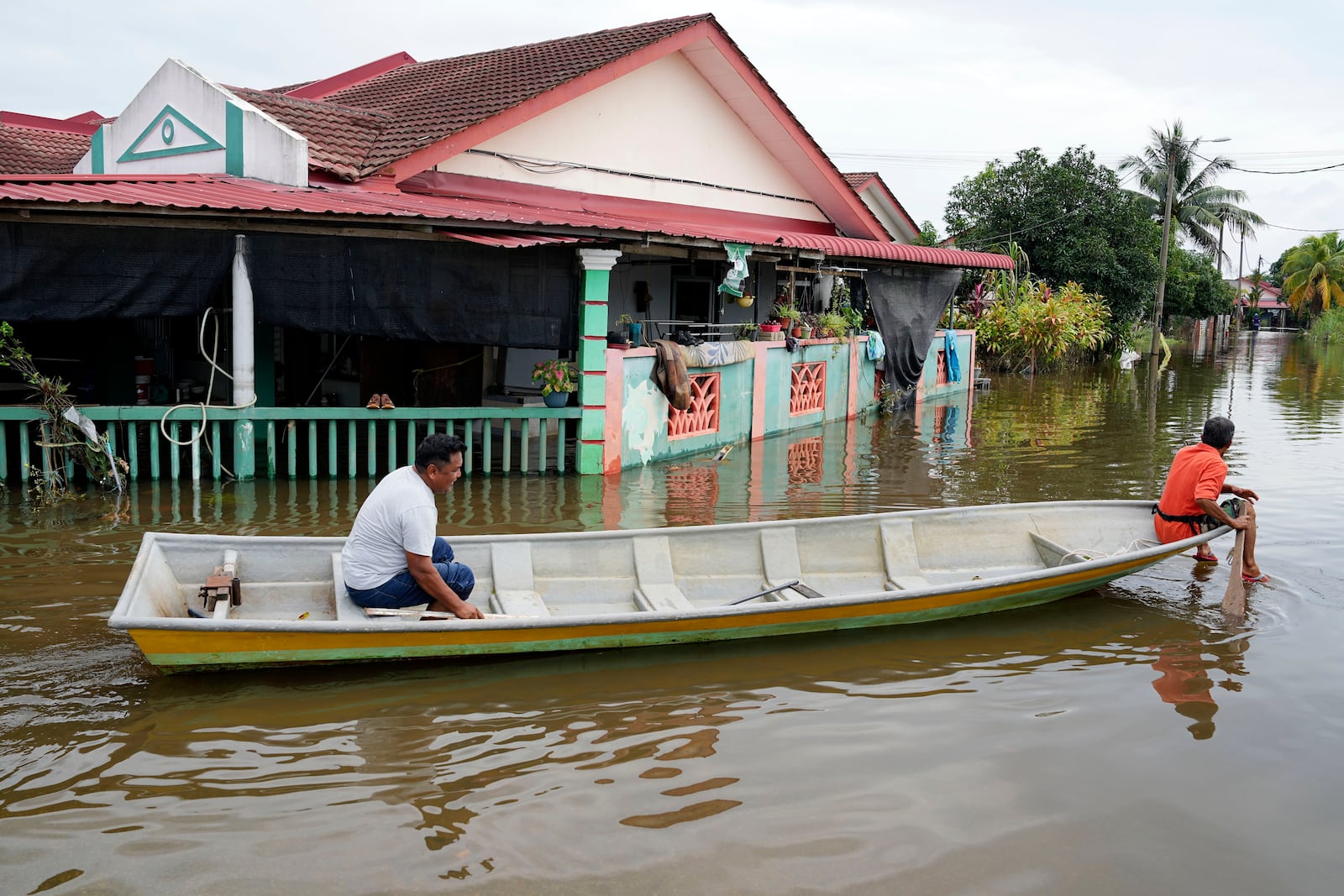 Men use a boat at a flooded neighborhood in Tumpat, on the outskirts of Kota Bahru, Malaysia, Tuesday, Dec. 3, 2024. (AP Photo/Vincent Thian)