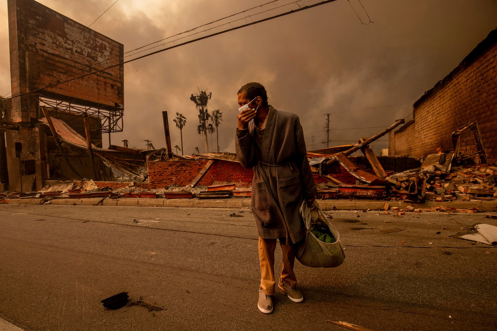 A man walks past a fire-ravaged business after the Eaton Fire swept through Wednesday, Jan. 8, 2025 in Altadena, Calif. (AP Photo/Ethan Swope)