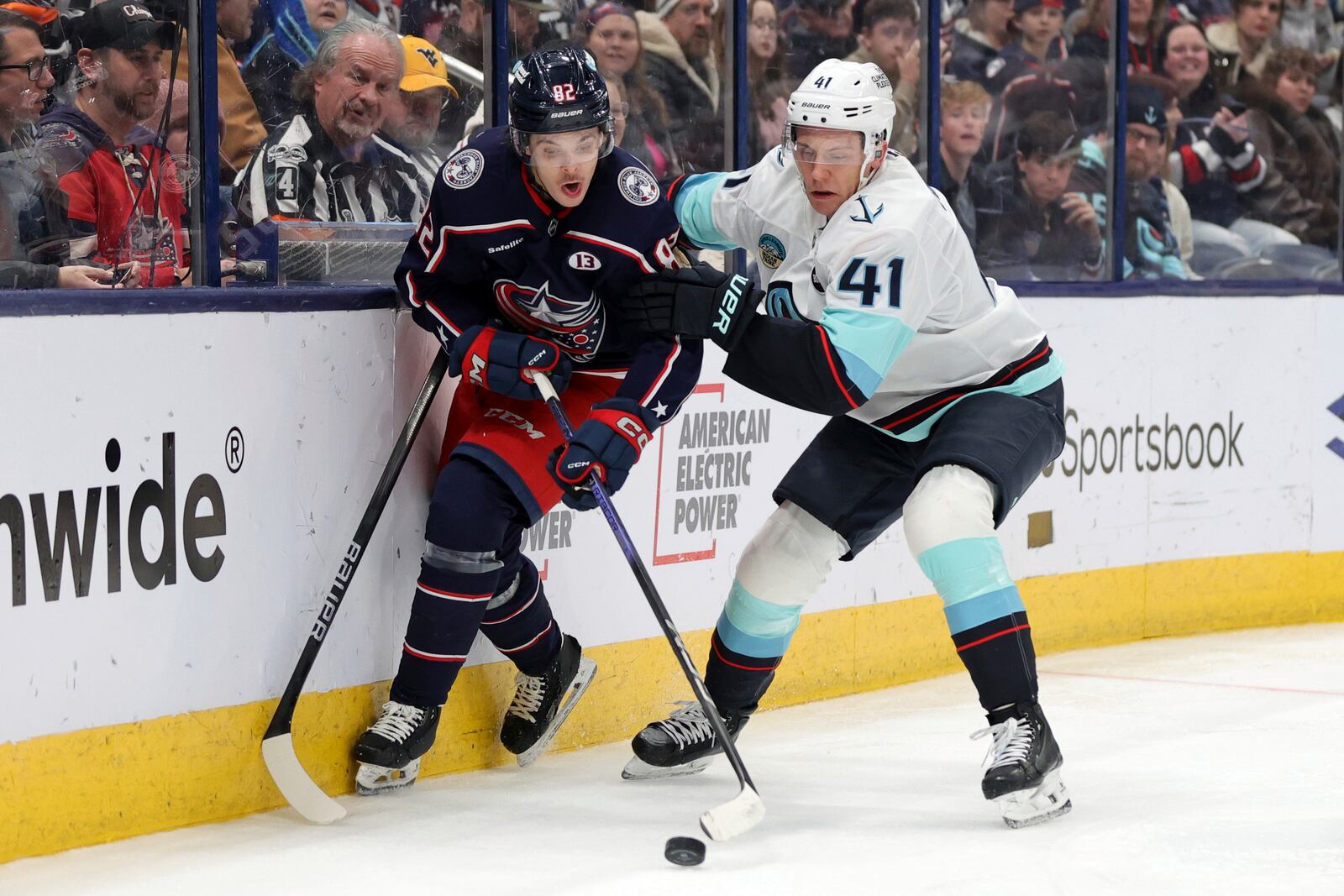 Columbus Blue Jackets forward Mikael Pyyhtia, left, reaches for the puck in front of Seattle Kraken defenseman Ryker Evans, right, during the second period of an NHL hockey game in Columbus, Ohio, Thursday, Jan. 9, 2025. (AP Photo/Paul Vernon)