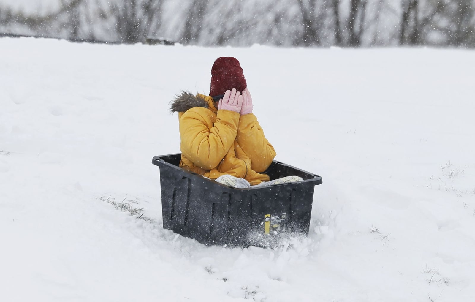 Miley Griffin, 11, sleds down a hill in a storage bin after an overnight snow Monday, Jan. 6, 2025 at St. John XXIII school in Middletown. NICK GRAHAM/STAFF