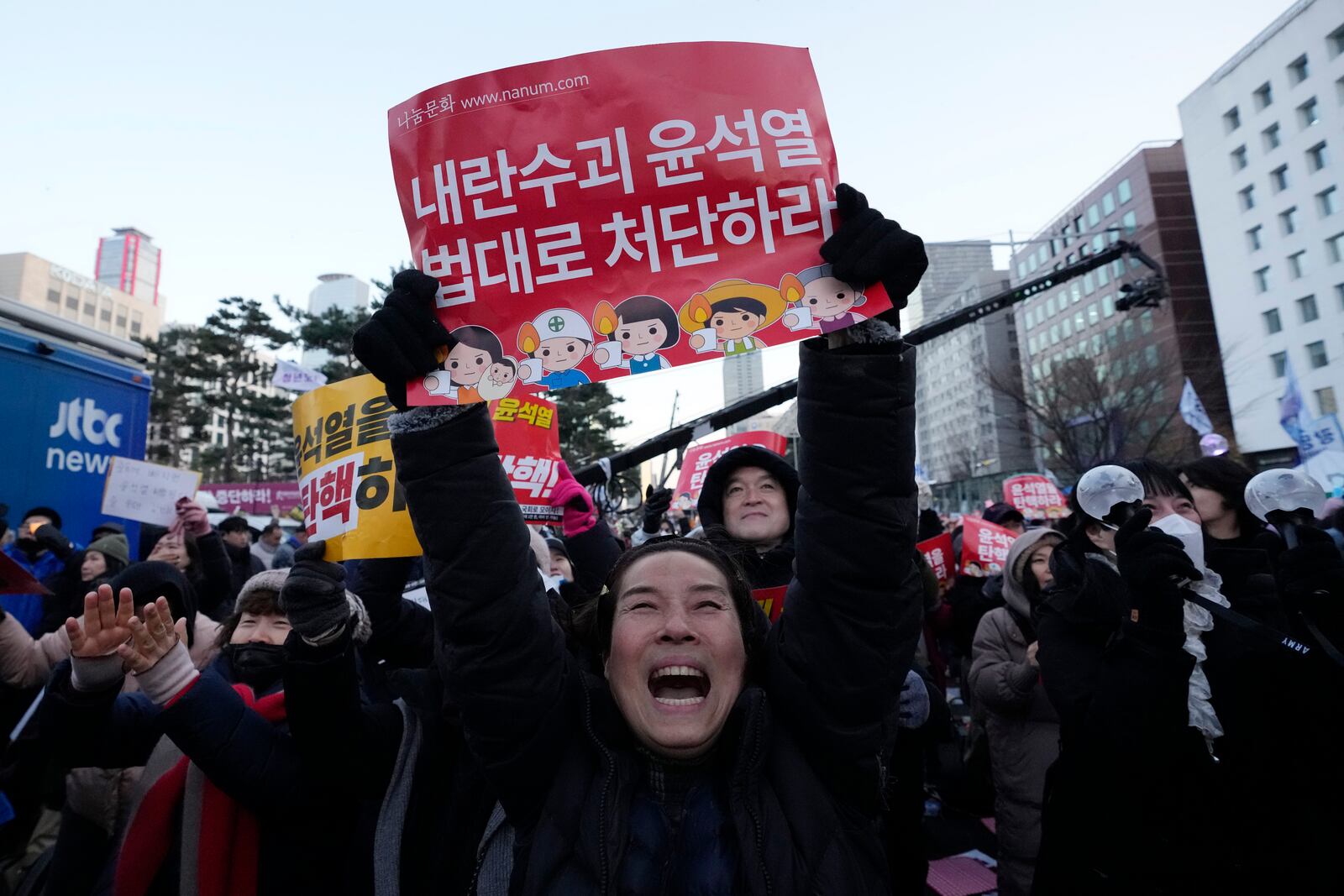 Participants celebrate after hearing the news that South Korea's parliament voted to impeach President Yoon Suk Yeol outside the National Assembly in Seoul, South Korea, Saturday, Dec. 14, 2024. The signs read "Punish the rebellion leader Yoon Suk Yeol." (AP Photo/Ahn Young-joon)