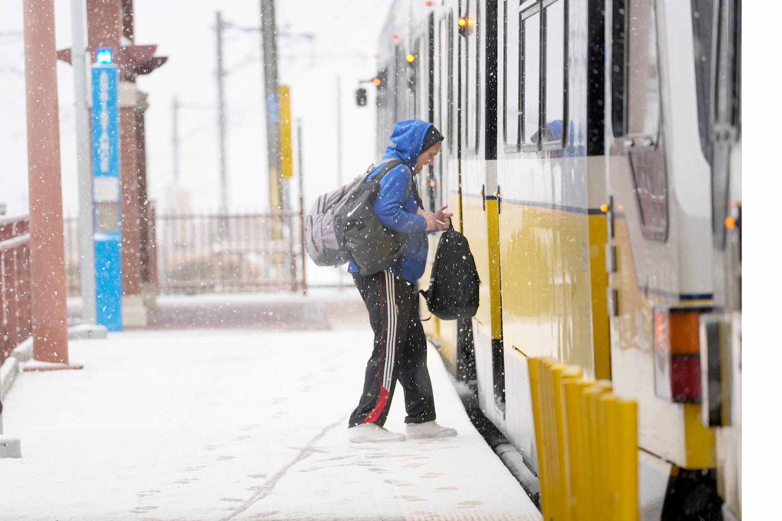 Snow falls as a person boards a DART train Thursday, Jan. 9, 2025, in Dallas. (AP Photo/LM Otero)