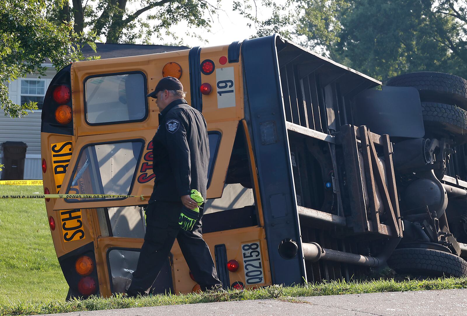 Clark County Sheriff's Lt. Kris Schultz walks past a Northwestern School District bus that was involved in a crash in Lawrenceville, Ohio, Tuesday, Aug. 22, 2023. (Bill Lackey/The Springfield News-Sun via AP)