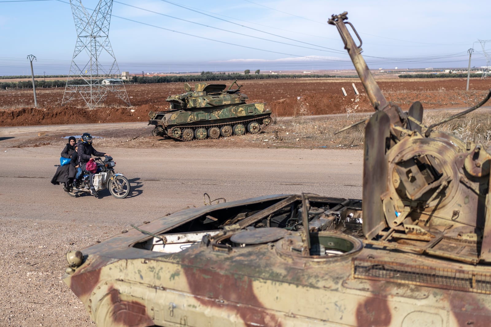 A family drives past tanks that belonged to the Assad regime, in Nawa, near Daraa, Syria, Jan. 4, 2025. (AP Photo/Mosa'ab Elshamy)