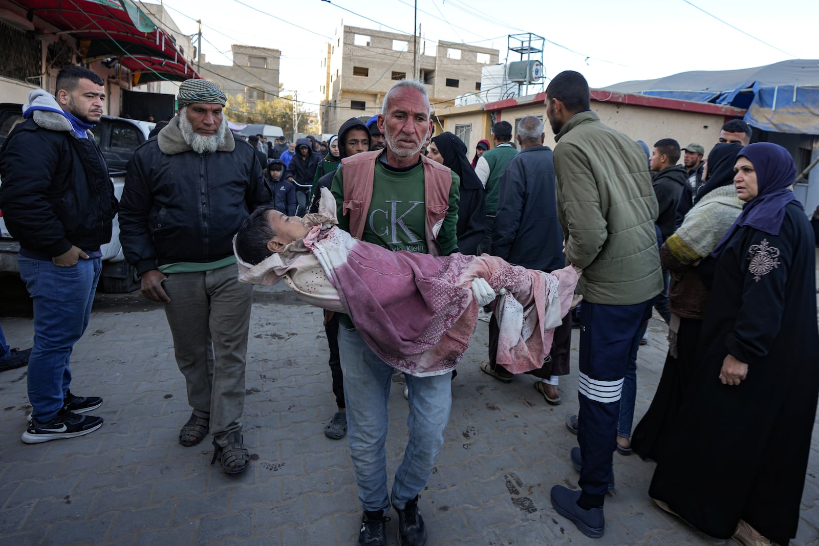 A Palestinian, holds the body of a child killed in the Israeli bombardment of the Gaza Strip, at Al-Aqsa Hospital in Deir al-Balah, Thursday, Dec. 19, 2024. (AP Photo/Abdel Kareem Hana)