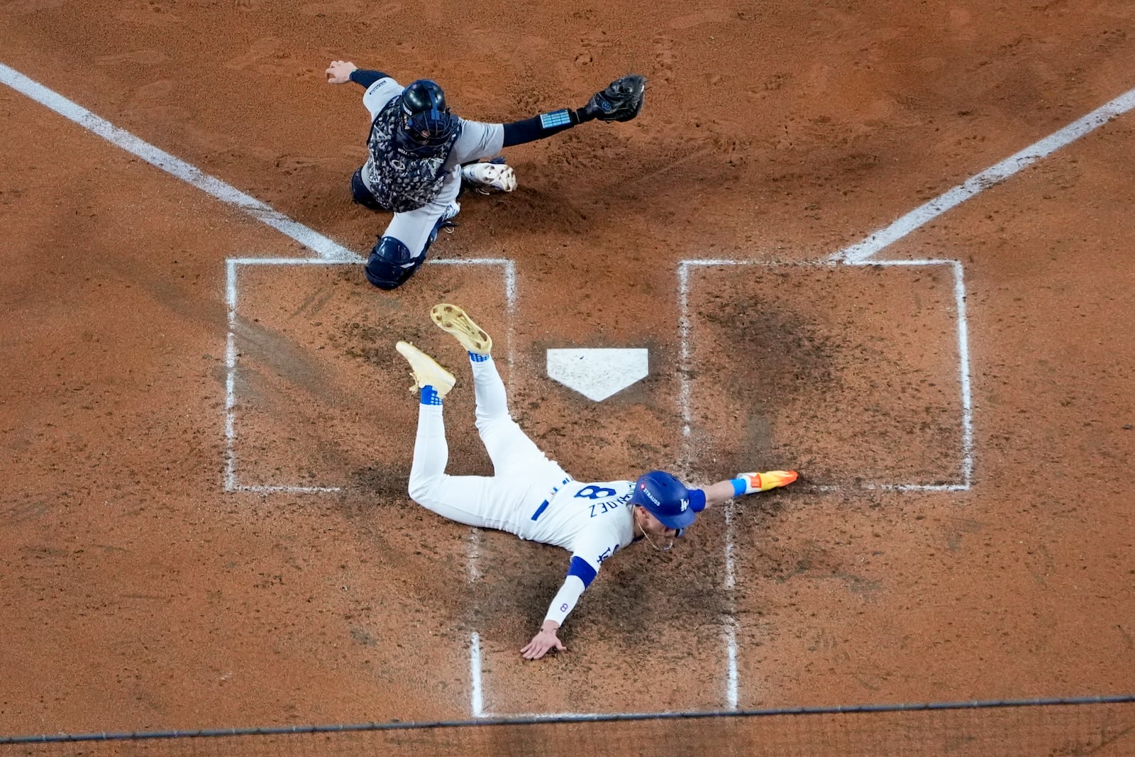 Los Angeles Dodgers' Enrique Hernández, bottom, scores past New York Yankees catcher Austin Wells on a sacrifice fly ball by Will Smith during the fifth inning in Game 1 of the baseball World Series, Friday, Oct. 25, 2024, in Los Angeles. (AP Photo/Mark J. Terrill)