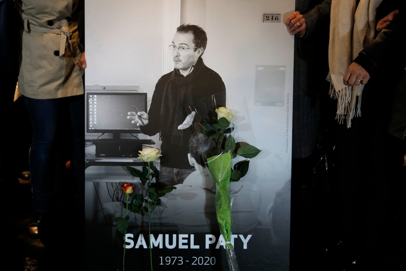 FILE - People hold a photo of the history teacher Samuel Paty , who was beheaded last week, during a memorial march in homage to him, Tuesday, Oct.20, 2020 in Conflans-Sainte-Honorine, northwest of Paris. (AP Photo/Lewis Joly, File)