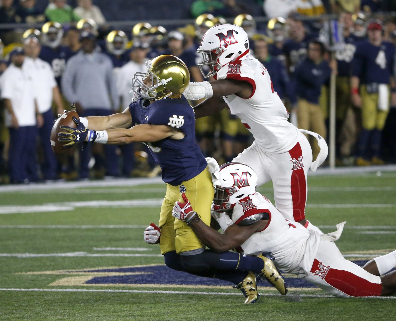 Notre Dame wide receiver Chris Finke, an Alter High School graduate, catches a 48-yard pass from Ian Book as Miami safety Josh Allen (top) and cornerback Deondre Daniels defend Saturday night during the host Fighting Irish’s 52-17 win at Notre Dame Stadium in Notre Dame, Ind. CHARLES REX ARBOGAST/ASSOCIATED PRESS