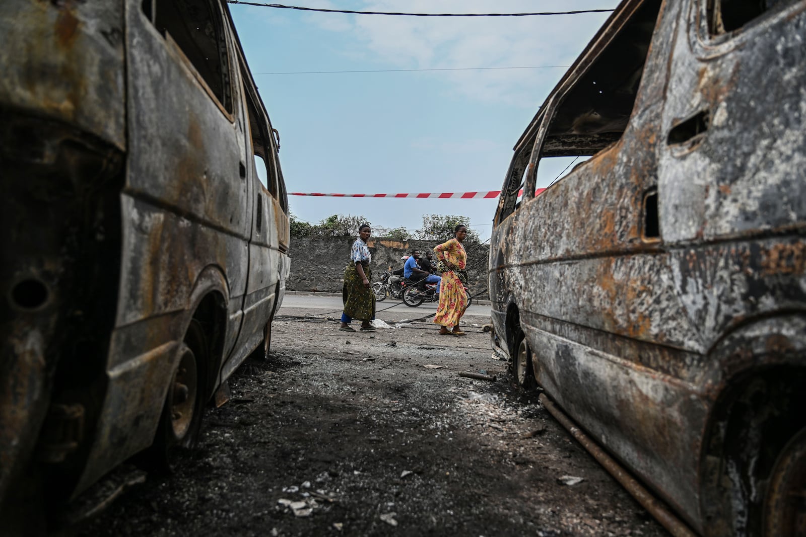 Residents walk by charred vehicles in Goma, Democratic republic of the Congo, Friday, Jan. 31, 2025. (AP Photo/Moses Sawasawa)