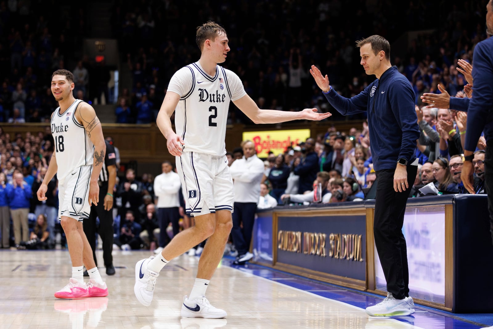 Duke's Cooper Flagg (2) high-fives Duke head coach Jon Scheyer, right, as he leaves the court late in the second half after scoring 42 points during an NCAA college basketball game against Notre Dame in Durham, N.C., Saturday, Jan. 11, 2025. (AP Photo/Ben McKeown)