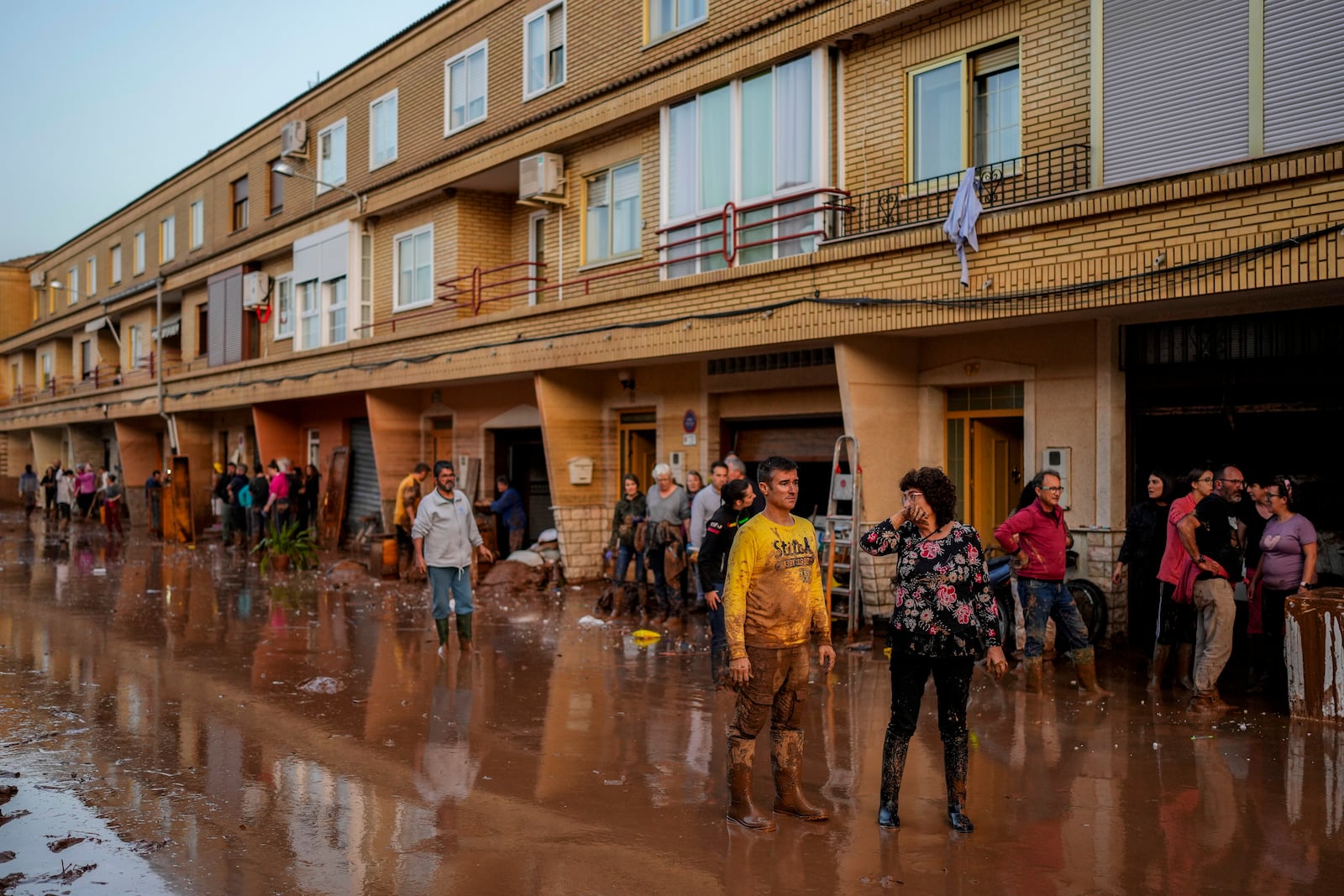 People stand in front of their houses affected by floods in Utiel, Spain, Wednesday, Oct. 30, 2024. (AP Photo/Manu Fernandez)