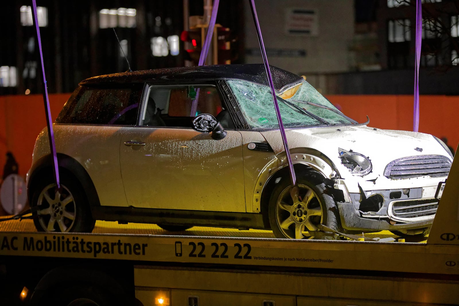 A car is lifted onto a tow truck at the scene where a driver drove a car into a labor union demonstration in Munich, Germany, Thursday Feb. 13, 2025. (Tizian Gerbing/dpa via AP)