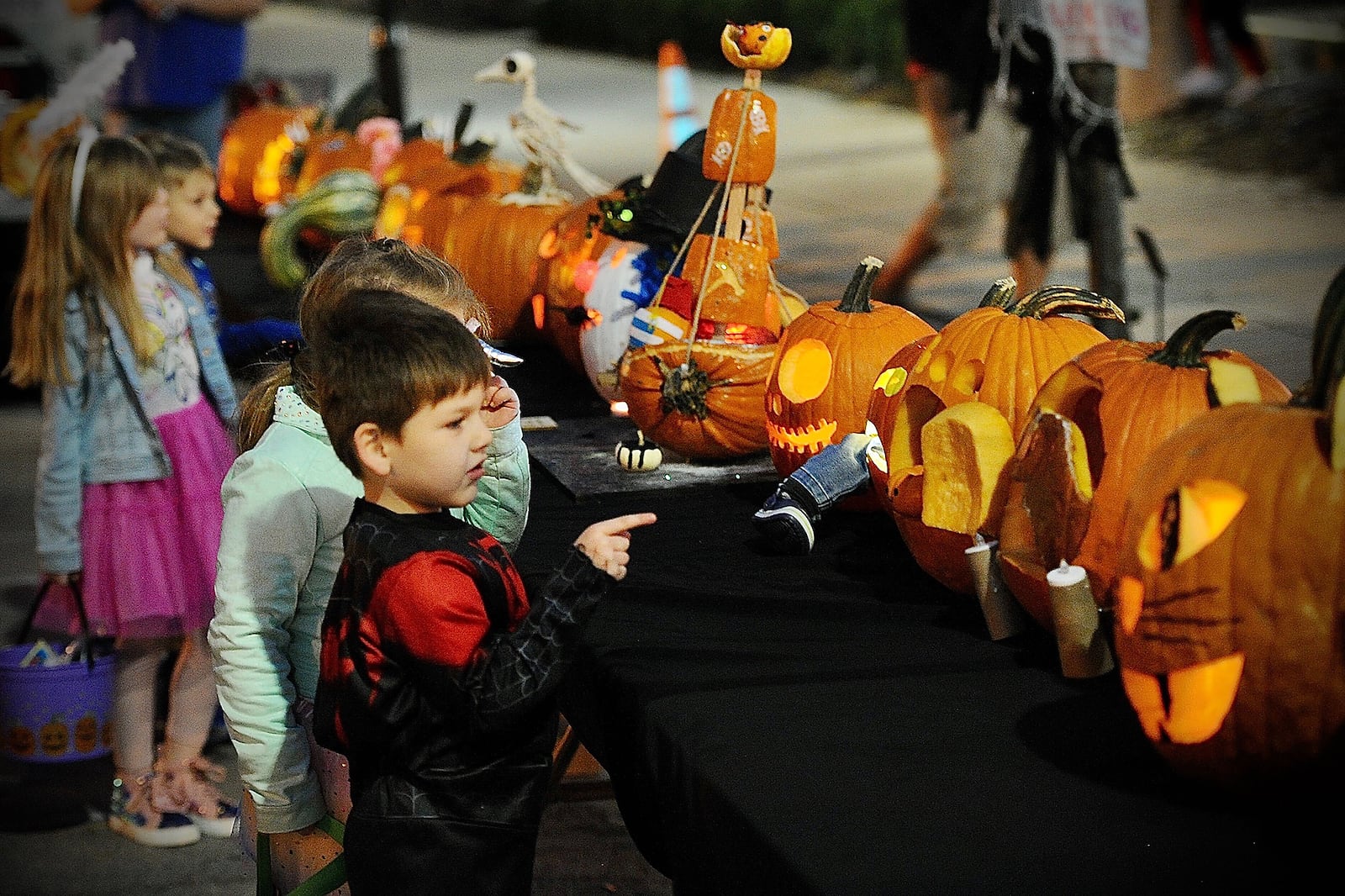 Children look over the pumpkins in the pumpkin carving contest Saturday during the New Carlisle Halloween Night Market. Marshall Gorby/Staff