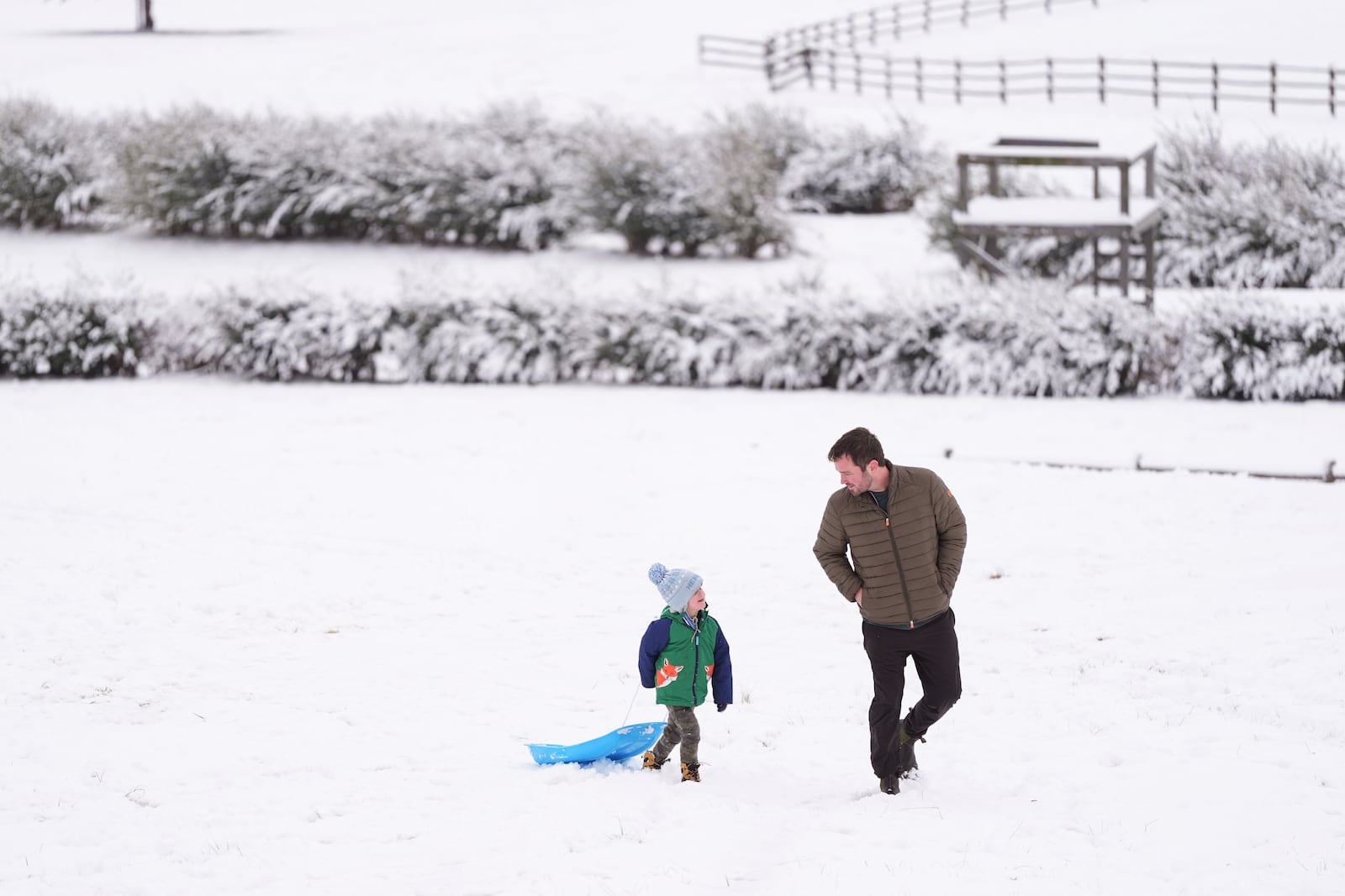 Henry Miller, left, walks up a snow covered hill with his father Nate, Saturday, Jan. 11, 2025, in Nashville, Tenn. (AP Photo/George Walker IV)