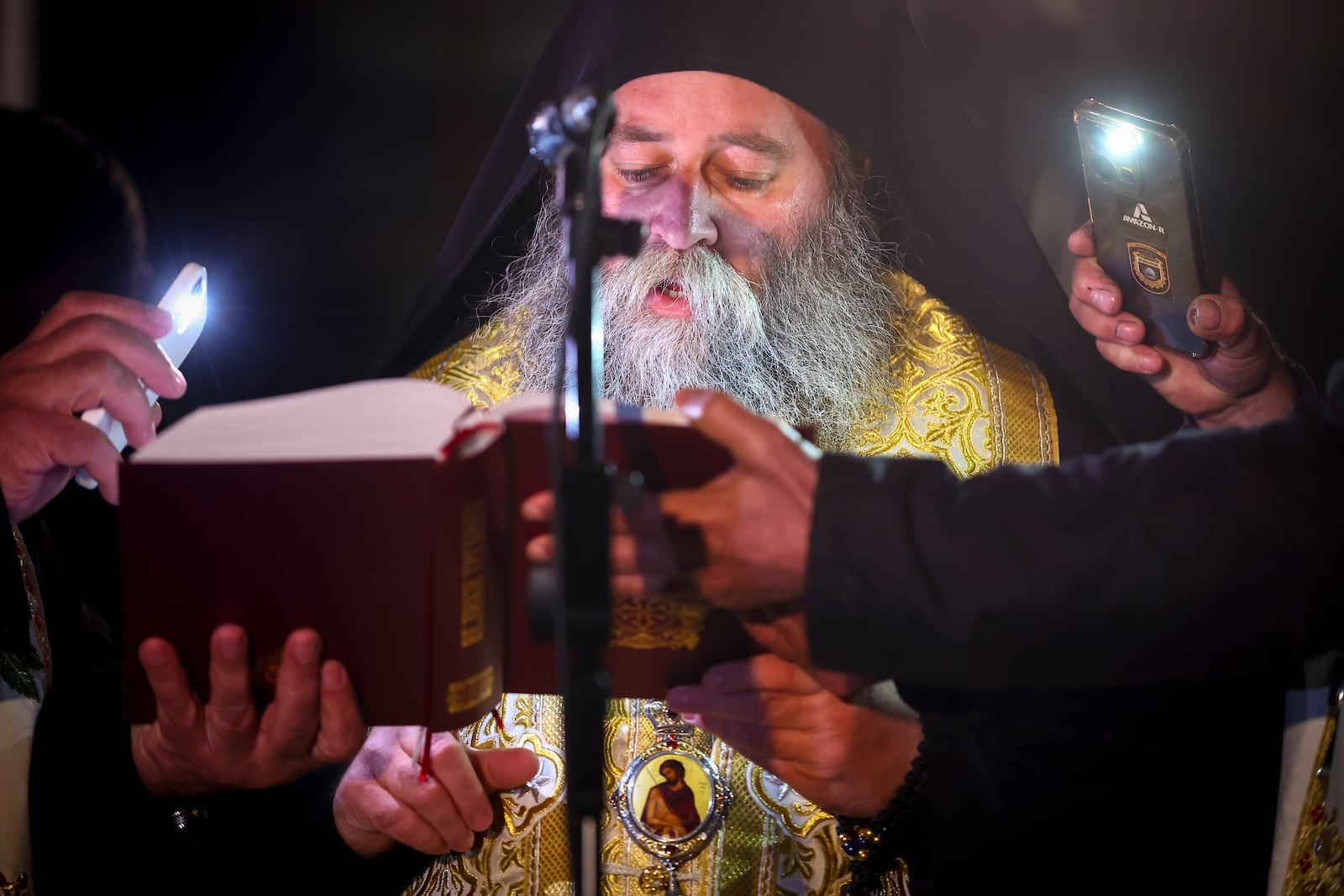 A priests reads prayers during a vigil in the town of Kocani, North Macedonia, Tuesday, March 18, 2025 following a massive fire in a nightclub early Sunday. (AP Photo/Armin Durgut)