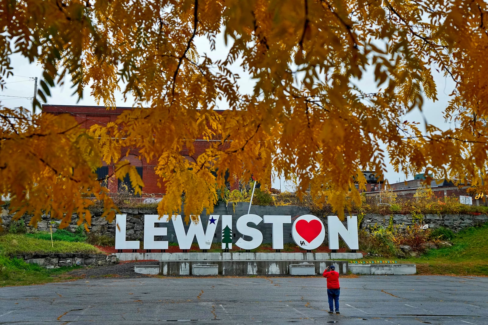 FILE - A man photographs a make-shift memorial at the base of the Lewiston sign at Veteran's Memorial Park, Oct. 29, 2023, in Lewiston, Maine. (AP Photo/Matt York, File)