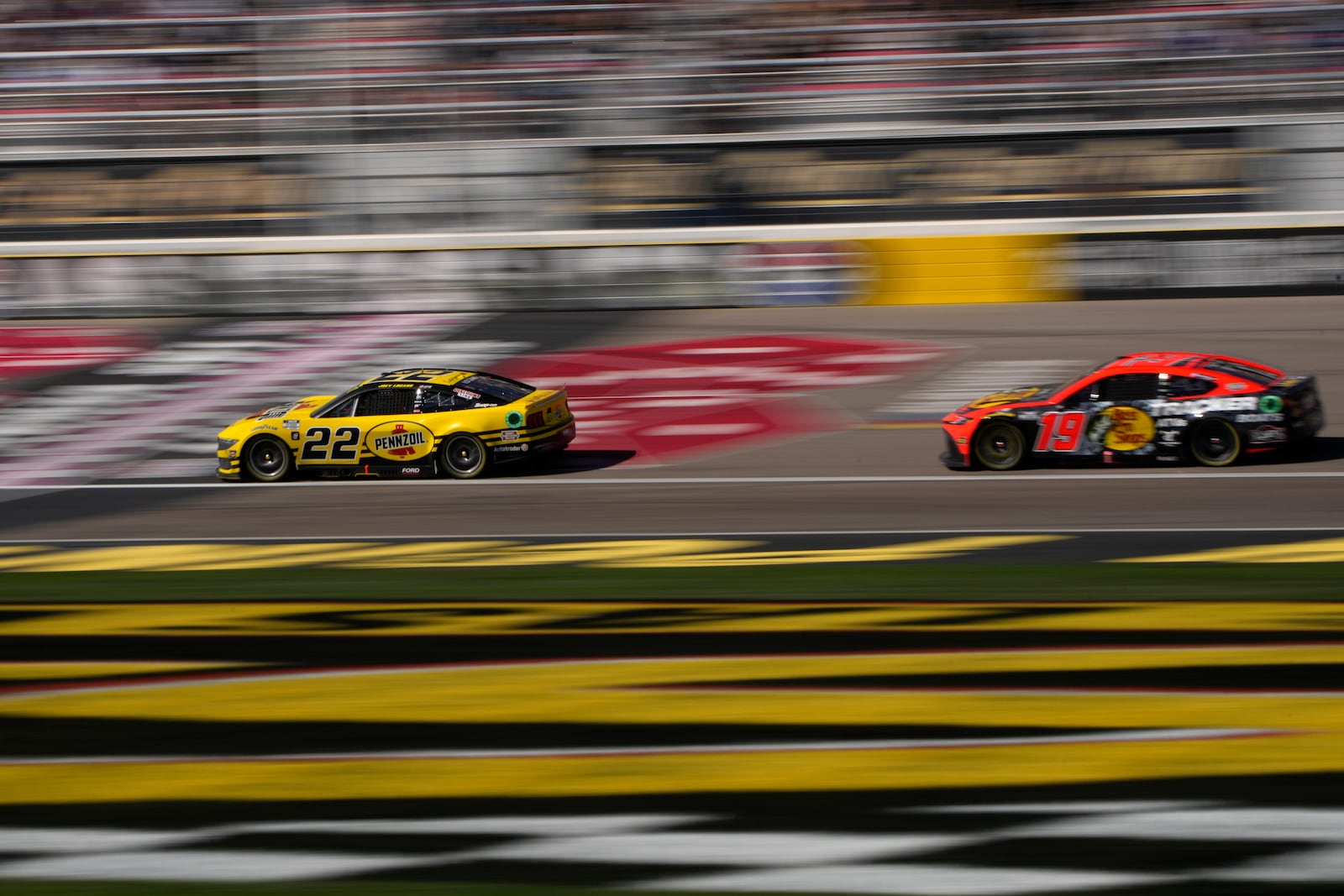 NASCAR Cup Series drivers Joey Logano (22) and Martin Truex Jr. (19) race during a NASCAR Cup Series auto race Sunday, Oct. 20, 2024, in Las Vegas. (AP Photo/John Locher)