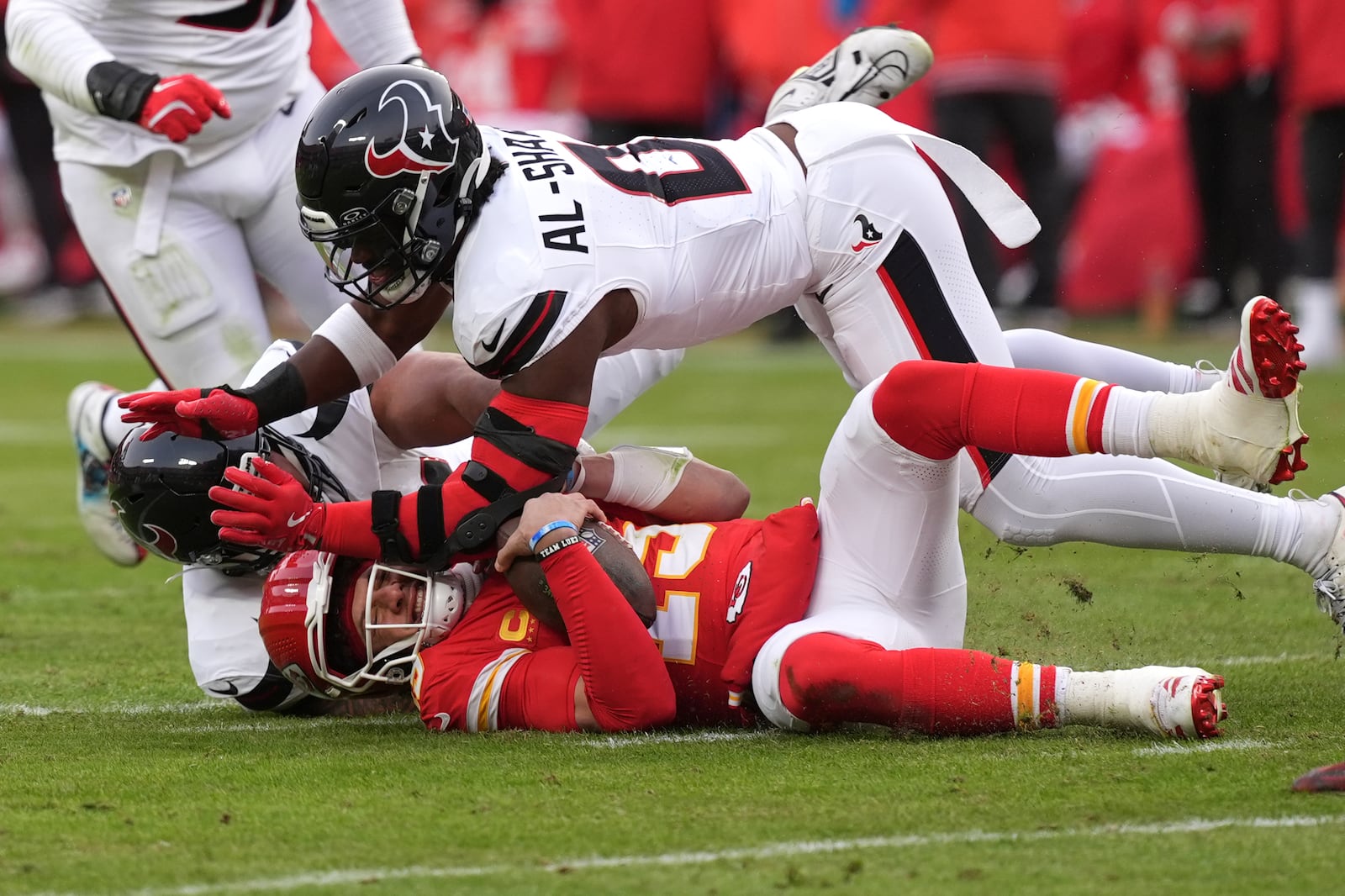 Kansas City Chiefs quarterback Patrick Mahomes, bottom, is stopped by Houston Texans running back Jawhar Jordan and linebacker Azeez Al-Shaair (0) during the first half of an NFL football AFC divisional playoff game Saturday, Jan. 18, 2025, in Kansas City, Mo. (AP Photo/Charlie Riedel)