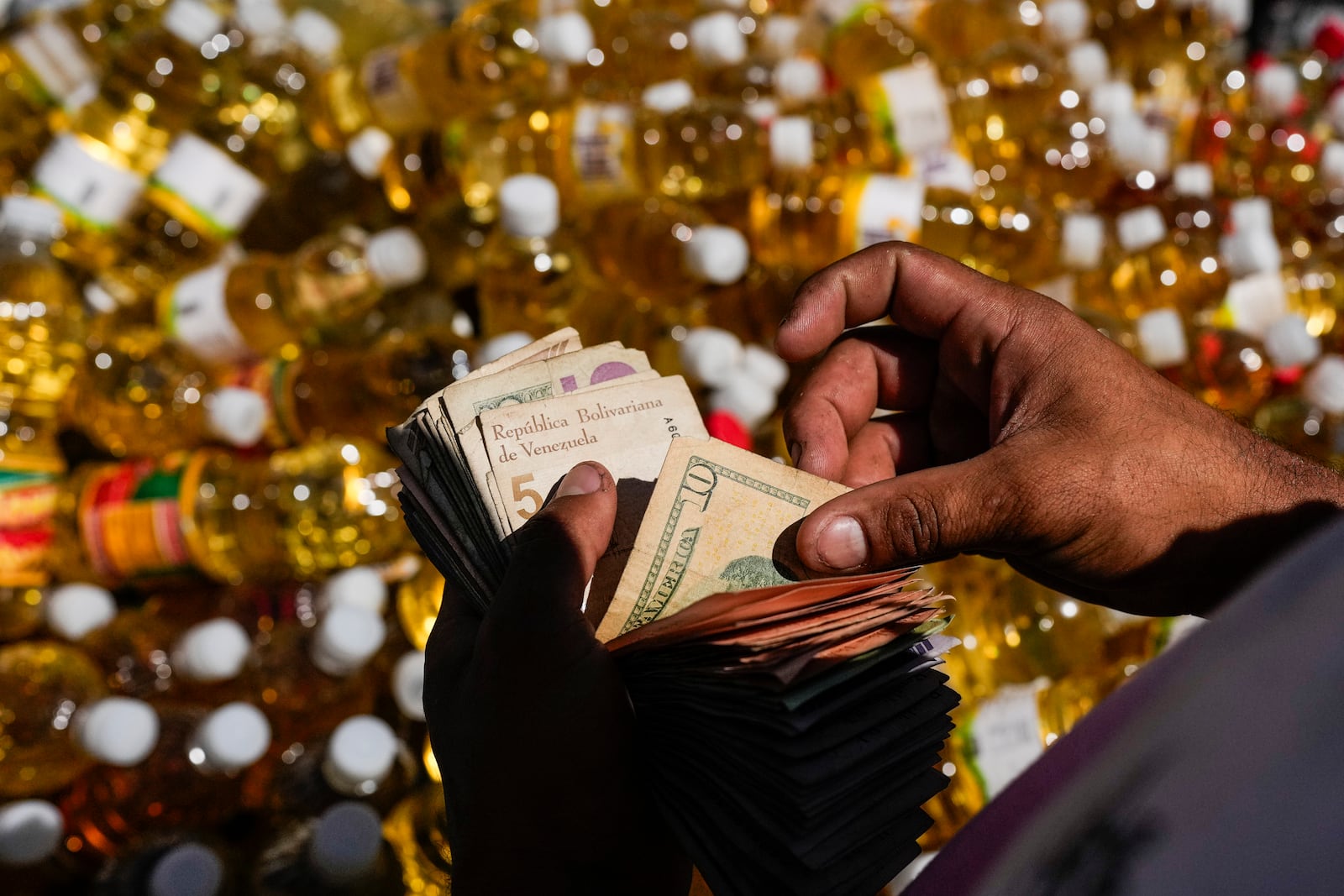 FILE - A vendor counts Venezuelan Bolivars and U.S. dollar bills as change for a customer at a public market in the Quinta Crespo neighborhood, in Caracas, Venezuela, Jan. 11, 2025. (AP Photo/Matias Delacroix, File)