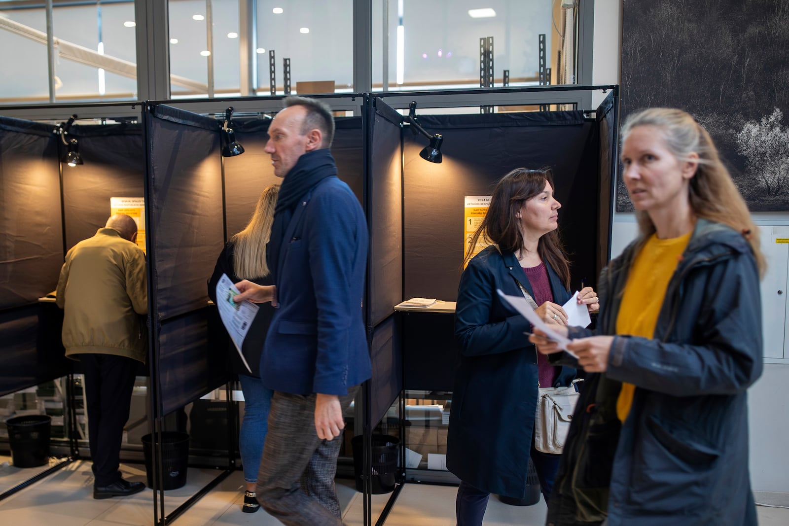 Local residents vote at the polling station during the advance voting in the first round of a parliamentary election in Vilnius, Lithuania, Wednesday, Oct. 9, 2024. (AP Photo/Mindaugas Kulbis)