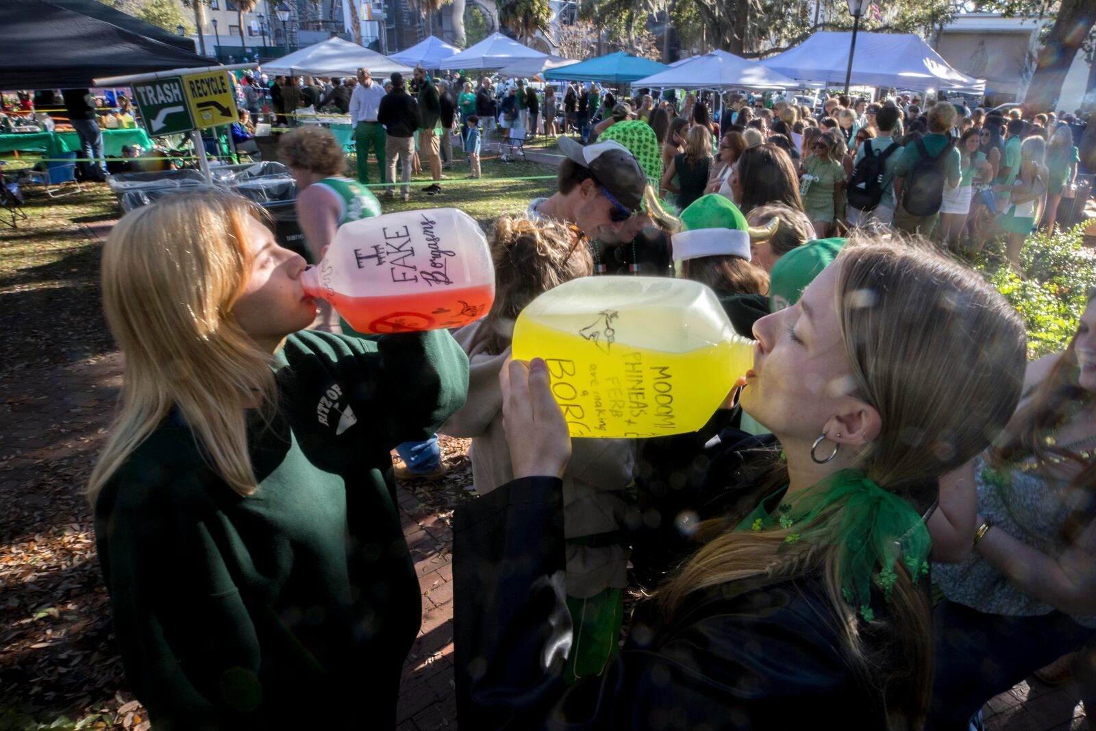 Bella Brykailo, left, and her friend Leighton Smith guzzle a non-alcoholic drink during the 201st anniversary of Savannah's St. Patrick's Day parade, Monday, March 17, 2025, in Savannah, Ga. (AP Photo/Stephen B. Morton)