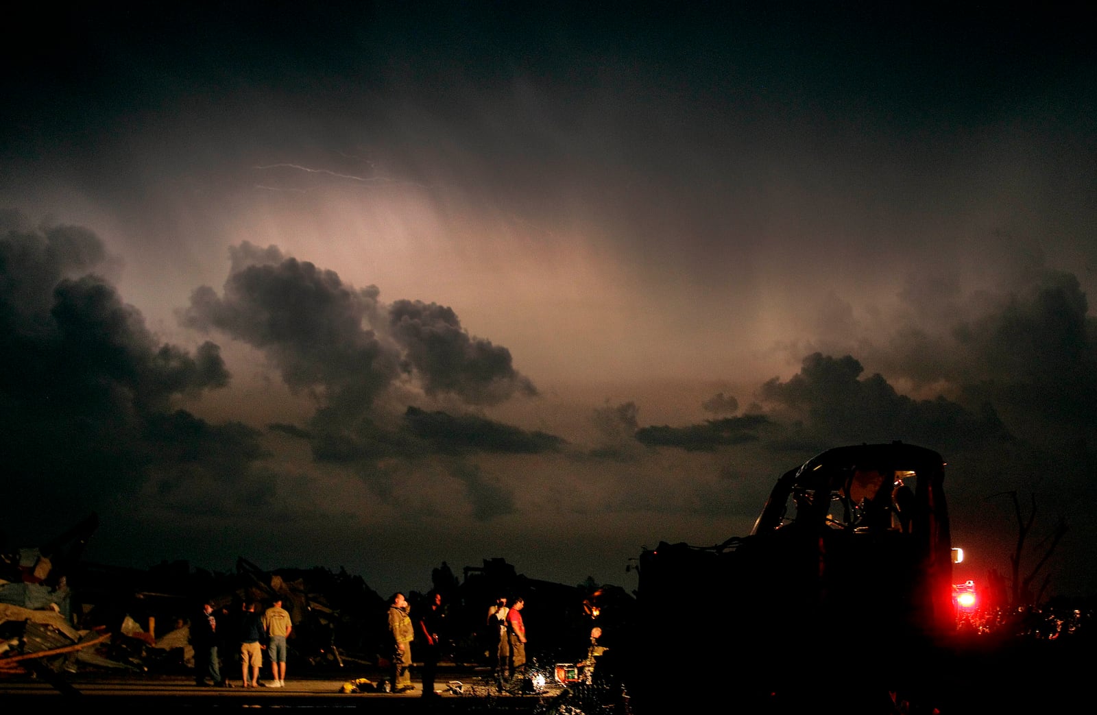 FILE- Emergency workers wait for a medical team after finding a body in a tornado ravaged car in Joplin, Mo., Monday, May 23, 2011. (AP Photo/Charlie Riedel, File)