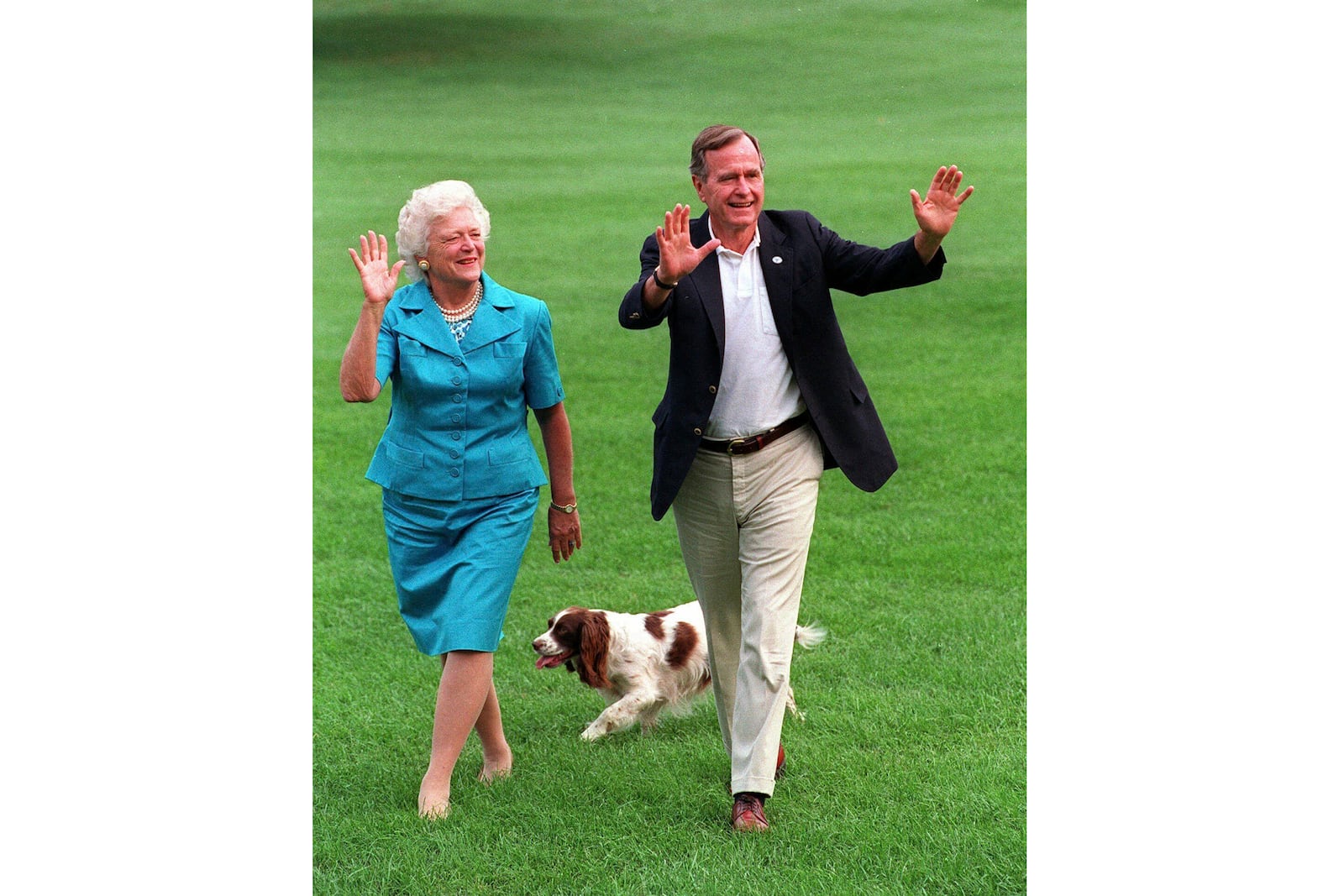 FILE- President Bush, right, and first lady Barbara Bush walking with their dog Millie across the South Lawn as they return to the White House, Aug. 24, 1992. (AP Photo/Scott Applewhite, File)