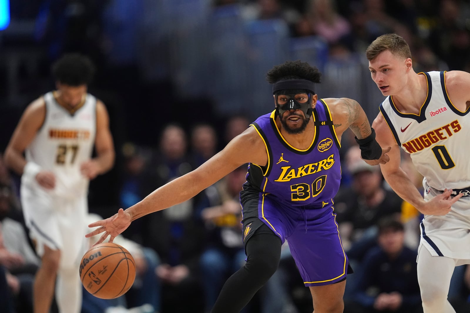 Los Angeles Lakers guard Jordan Goodwin, left, collects a loose ball as Denver Nuggets guard Christian Braun defends in the first half of an NBA basketball game Saturday, Feb. 22, 2025, in Denver. (AP Photo/David Zalubowski)