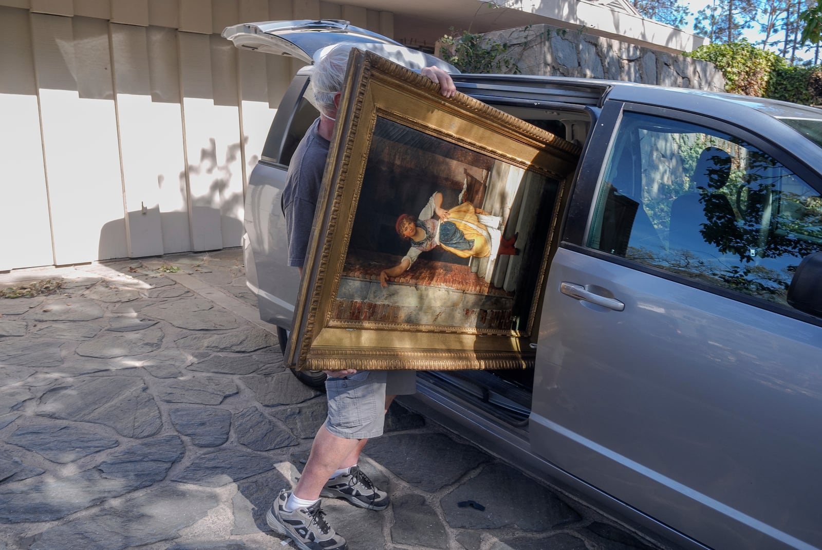 A resident retrieves an oil painting titled "Washer" from a surviving residence in the Pacific Palisades neighborhood of Los Angeles, Friday, Jan. 24, 2025. (AP Photo/Damian Dovarganes)