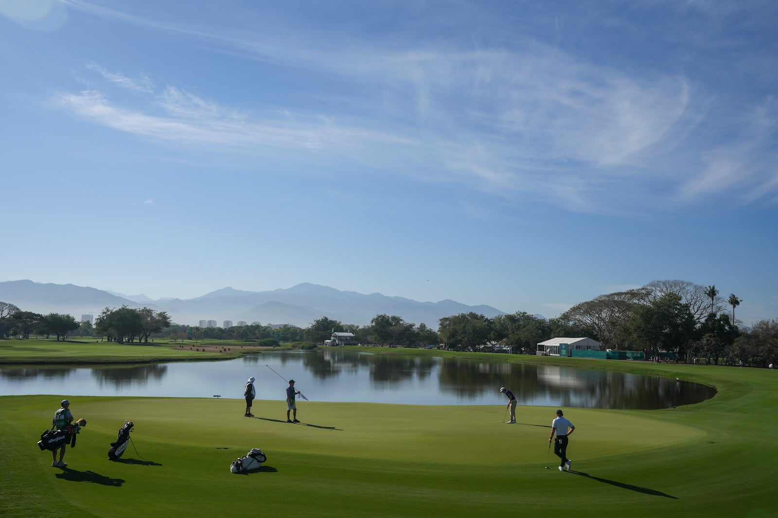 Justin Hastings, of Cayman Islands, second right, watches his putt on the green of the first hole during the third round of the Mexico Open golf tournament in Puerto Vallarta, Mexico, Saturday, Feb. 22, 2025. (AP Photo/Fernando Llano)