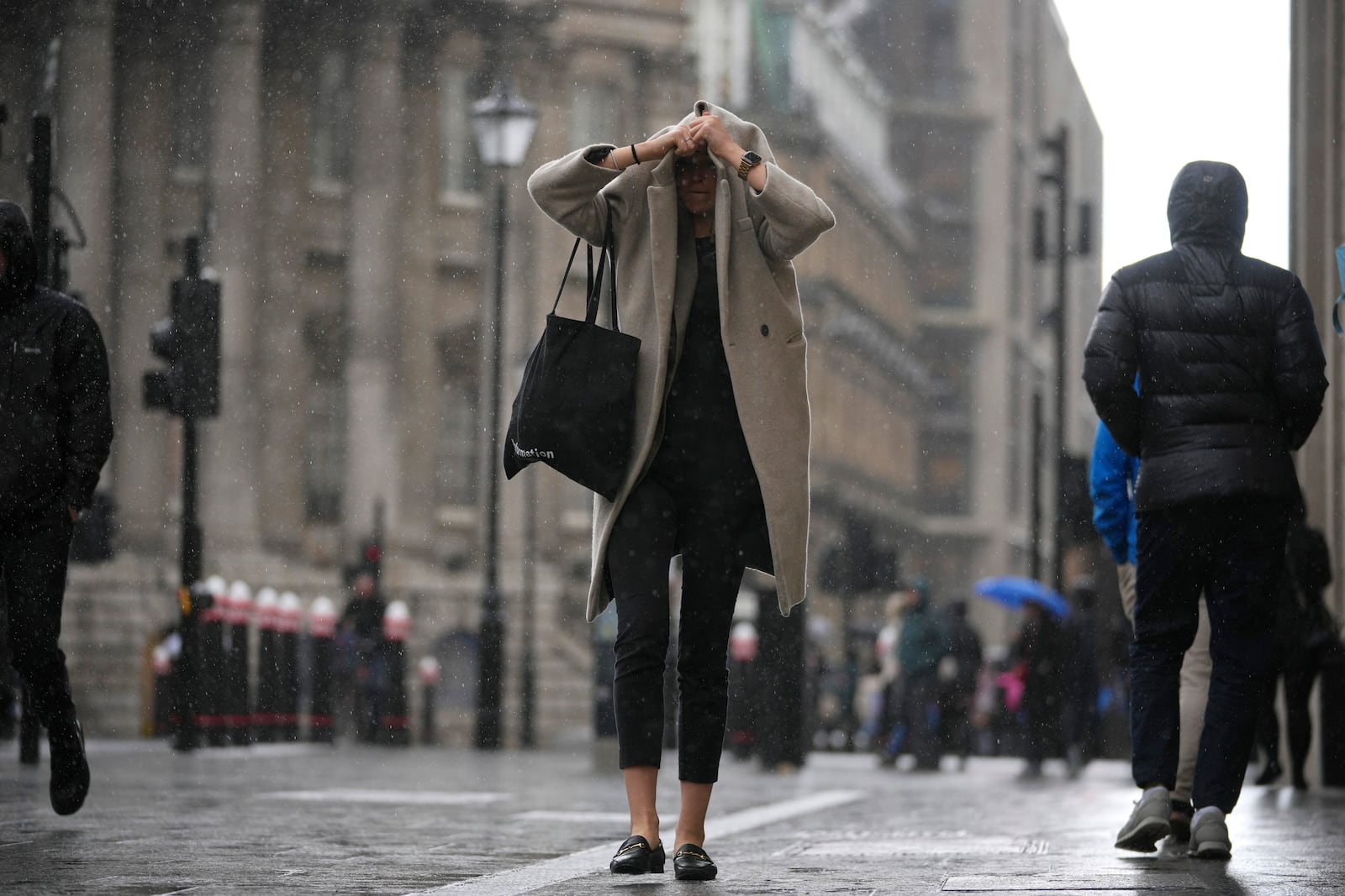 A woman walks past the Bank of England, at the financial district, in London, Thursday, March 13, 2025. (AP Photo/Kin Cheung)