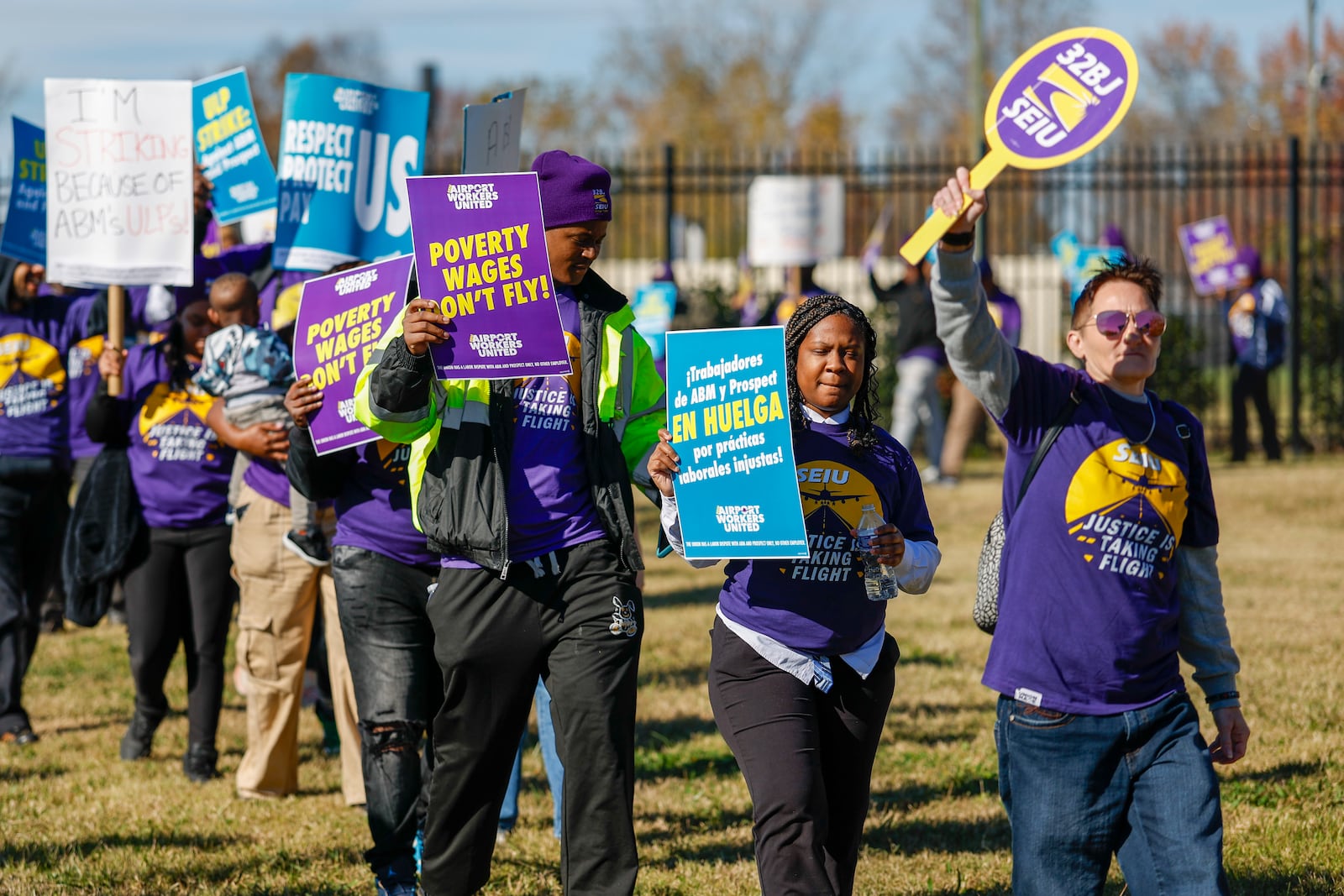 Airport workers wave signs as they march in front of the Charlotte Douglas International Airport in Charlotte, N.C., Monday, Nov. 25, 2024. (AP Photo/Nell Redmond)