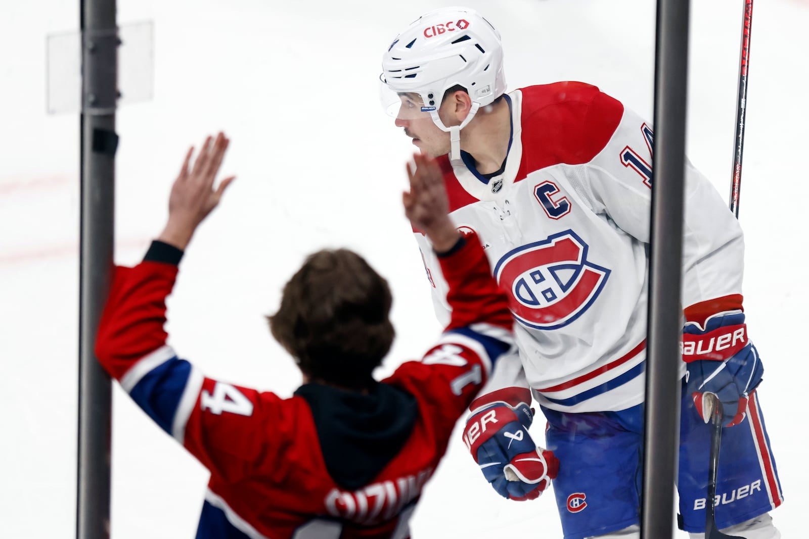 Montreal Canadiens forward Nick Suzuki, right, skates in front of a fan after scoring the game-winning overtime goal against the Columbus Blue Jackets during an NHL hockey game in Columbus, Ohio, Wednesday, Nov. 27, 2024. (AP Photo/Paul Vernon)