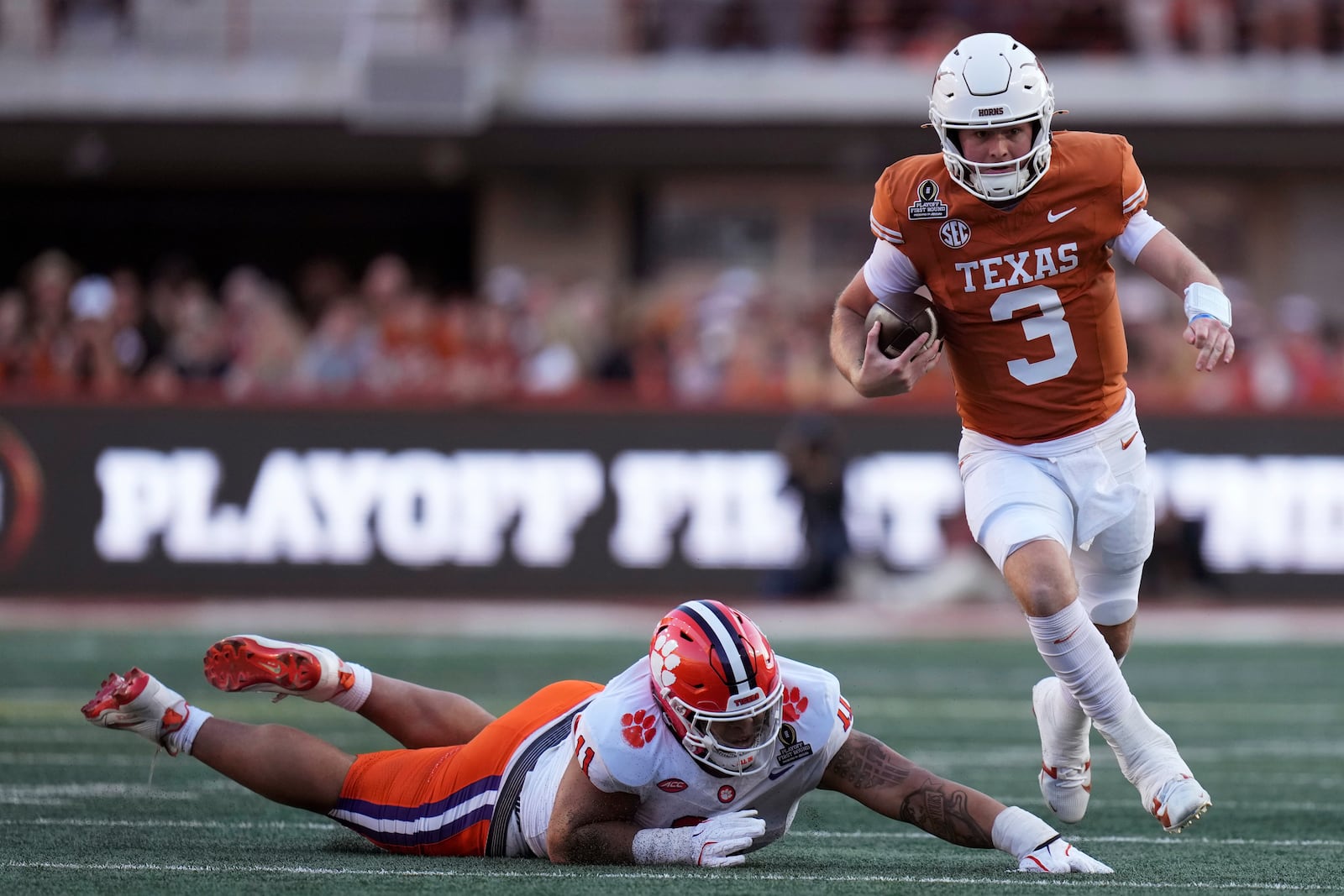 Texas quarterback Quinn Ewers (3) runs from Clemson defensive lineman Peter Woods during the first half in the first round of the College Football Playoff, Saturday, Dec. 21, 2024, in Austin, Texas. (AP Photo/Eric Gay)